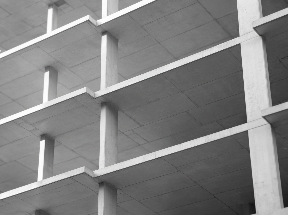 Black and white photo of an unfinished concrete building with multiple open floors and structural beams.