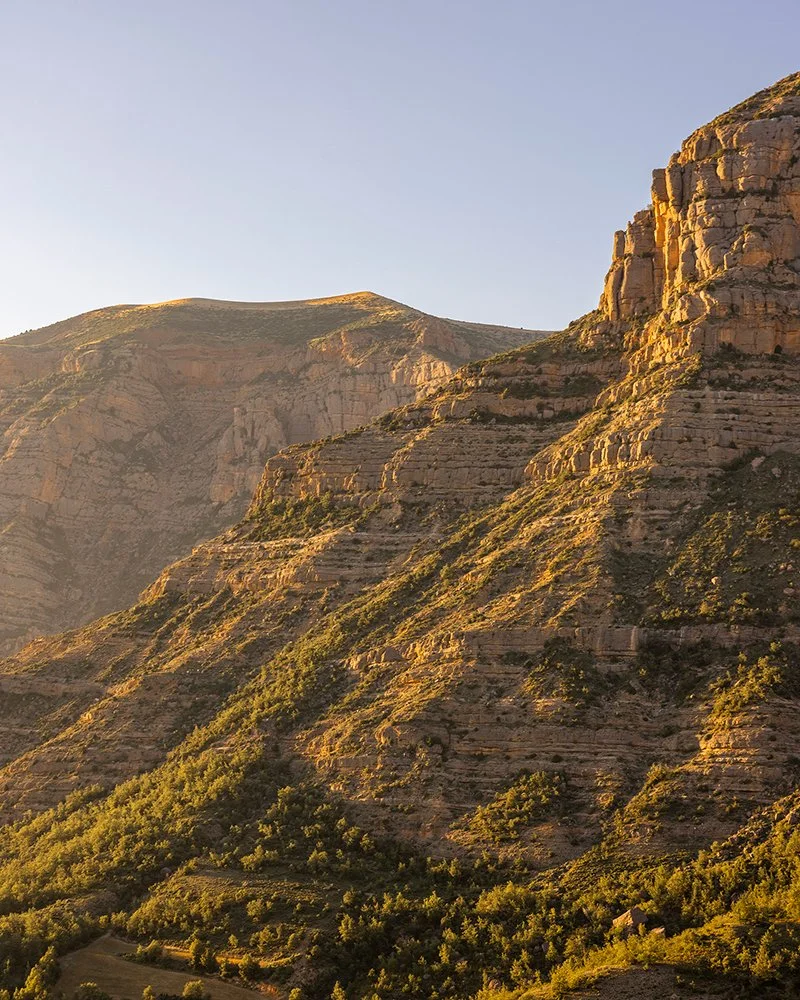 Vista panorámica de montañas y tierra agrícola en un valle con cielo nublado.
