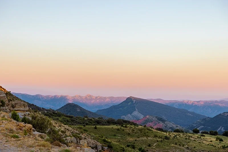 Río que pasa por un valle con casas en las colinas y árboles verdes