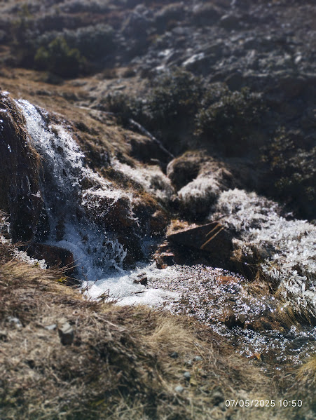 Una cascada pequeña en un río de montaña con agua cristalina y rocas alrededor, en un entorno natural.