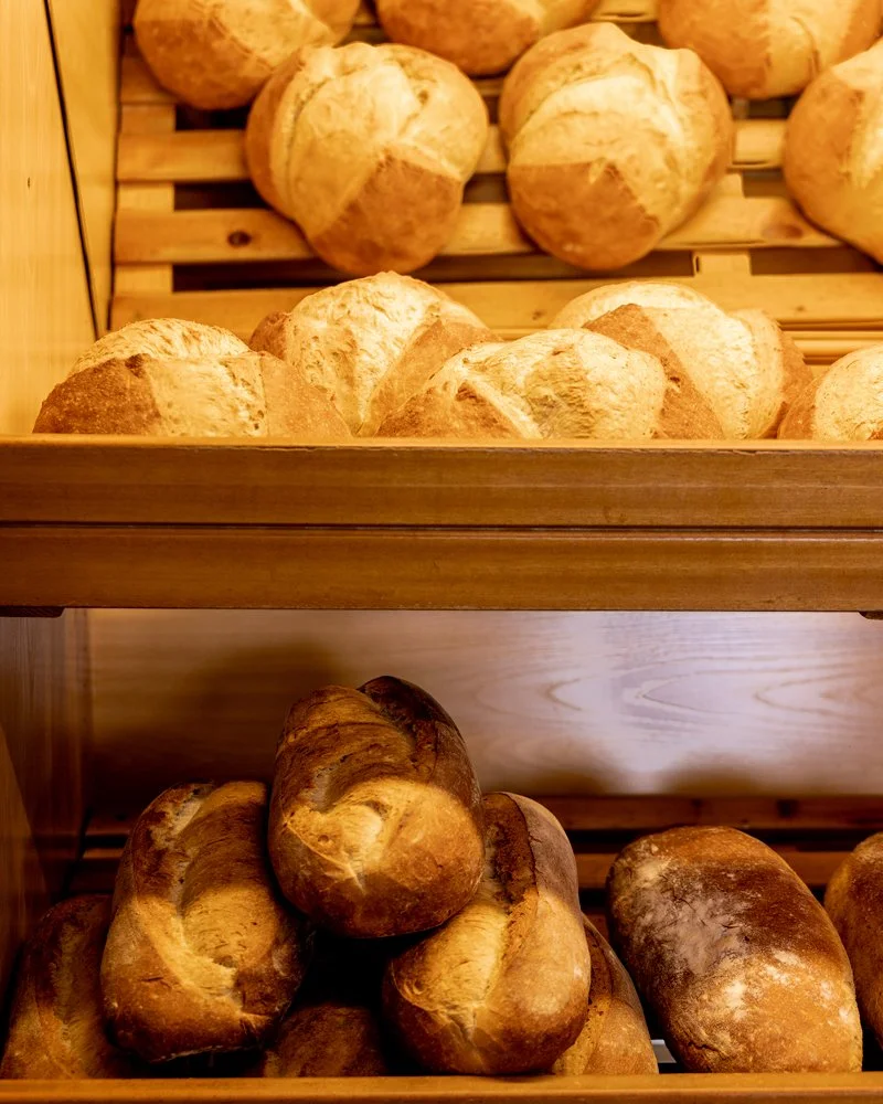 Pan artesanal en estantes de madera en una panadería.