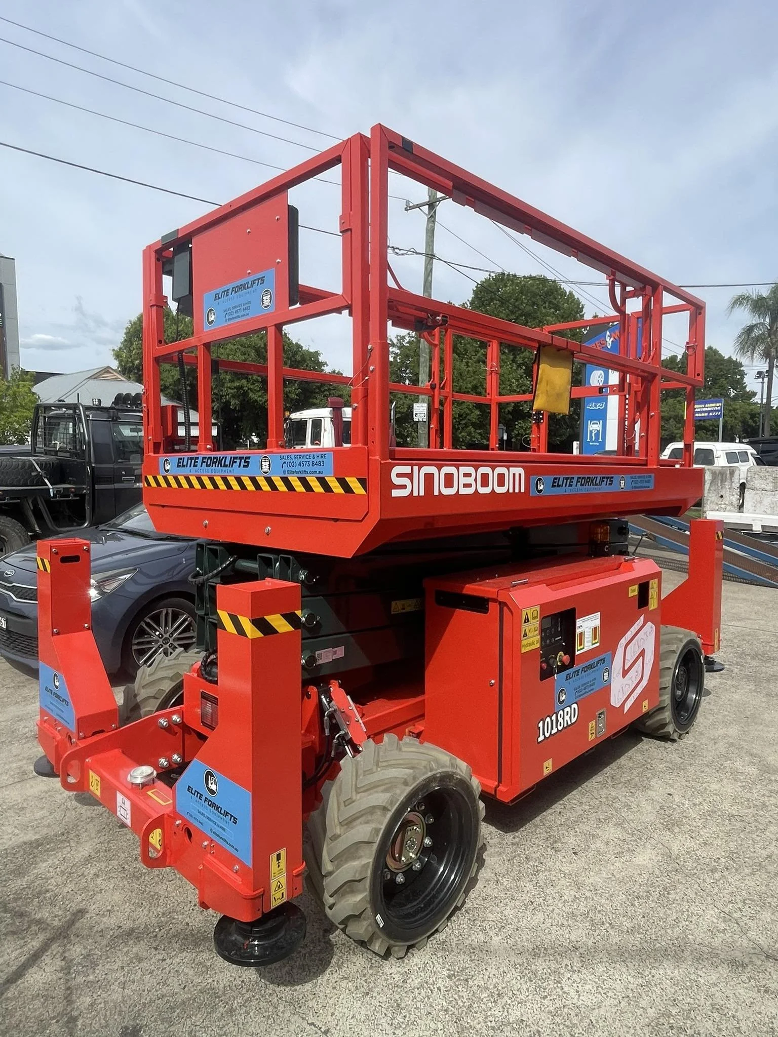 Yellow scissor lift inside a warehouse, with safety rails and control panel.