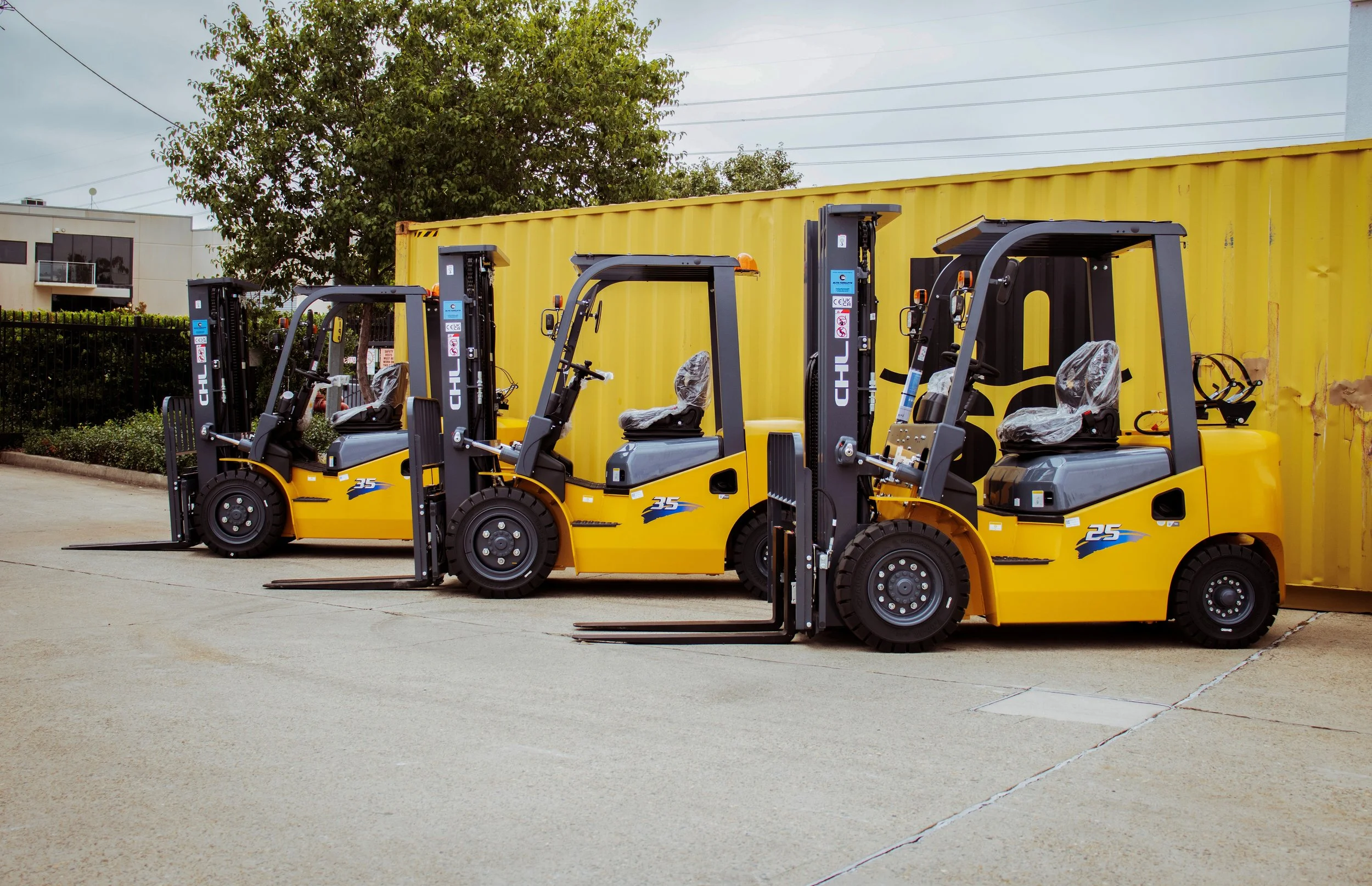A man operating a forklift and another man stacking bricks outdoors on a sunny day.