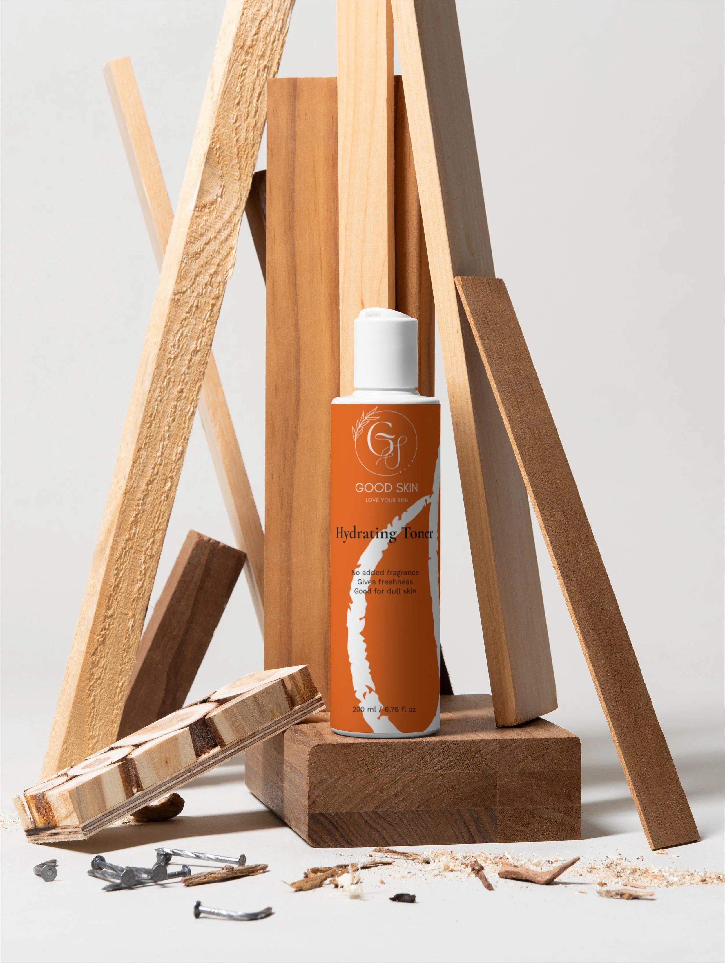 Bottle of Good Skin Hydrating Toner standing among scattered wood pieces and nails, with wooden planks arranged in the background.