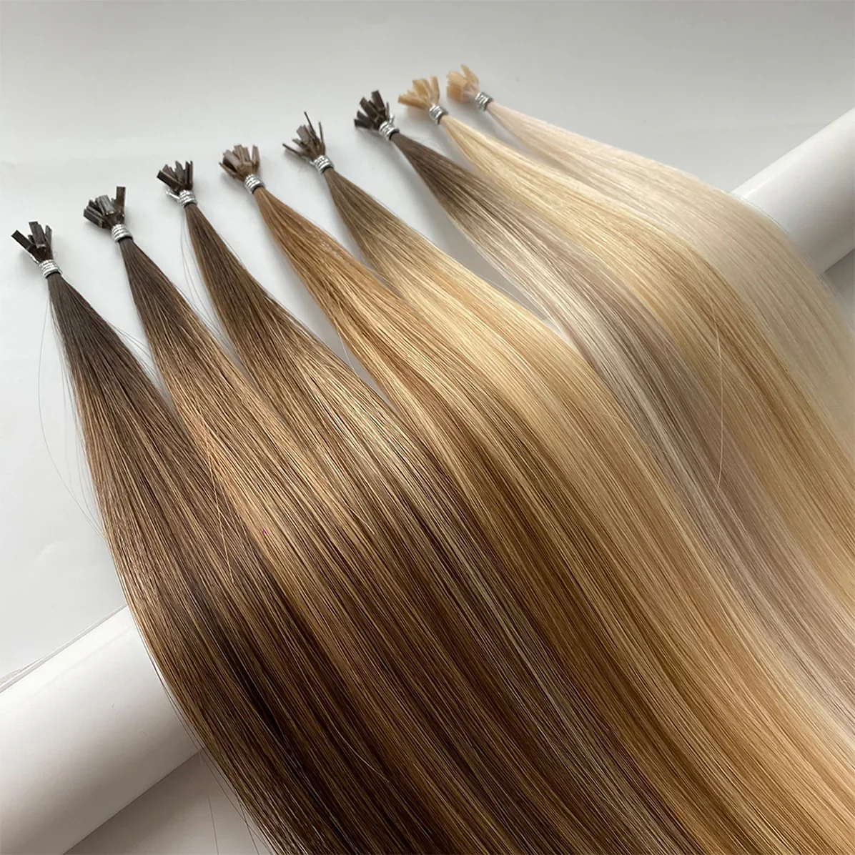 Assorted hair extensions in various shades of blonde, brown, and dark blonde, laid out in a row.