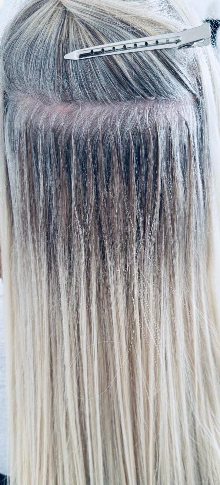 Close-up of a person's scalp with blonde hair sectioned off, held in place by a hair clip, with the hair freshly dyed blonde.