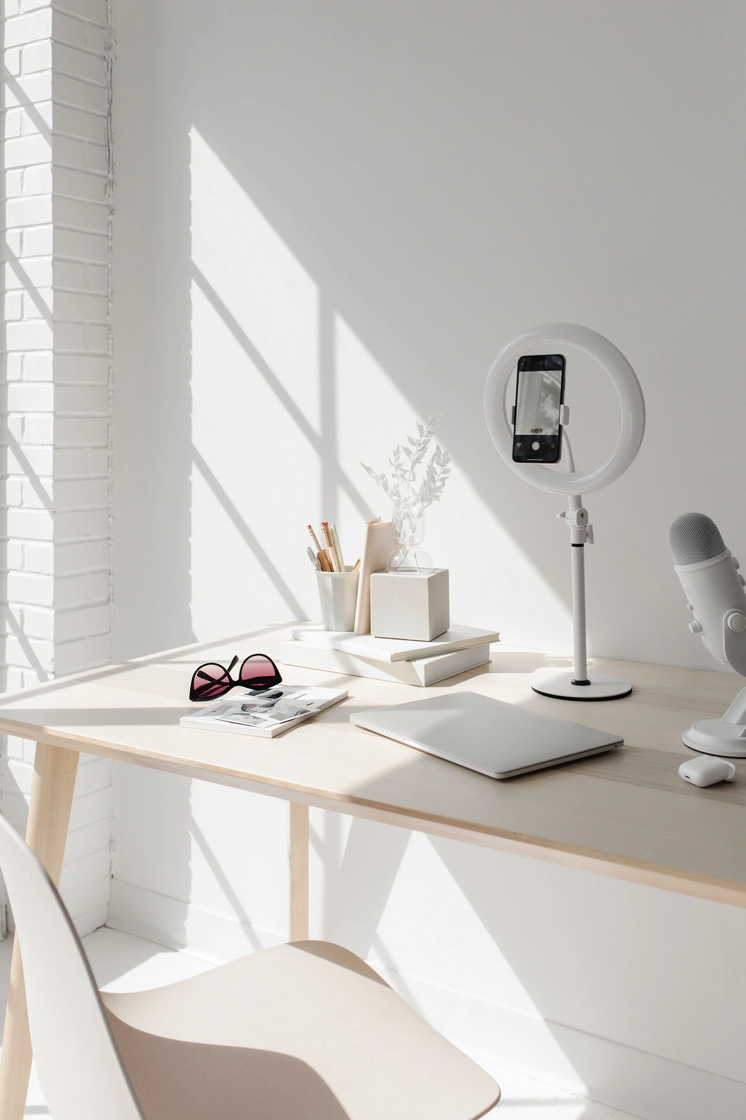 office desk with laptop, ring light with mobile phone and microphone social media tools