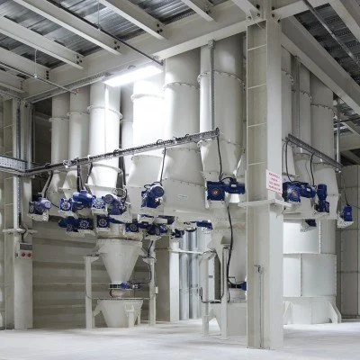 Industrial equipment with large white pipes and blue valves in a factory or processing plant.