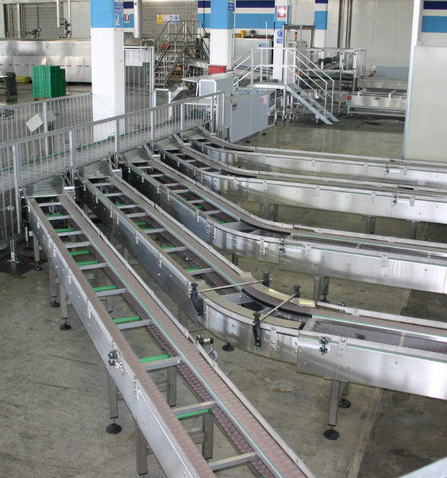 Industrial conveyor system with multiple metal tracks and pathways in a large factory or warehouse setting.