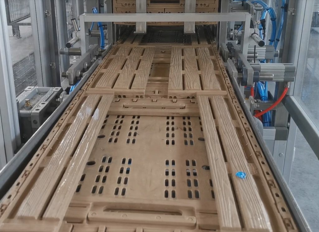 A conveyor system moving wooden pallets through a manufacturing or assembly process.
