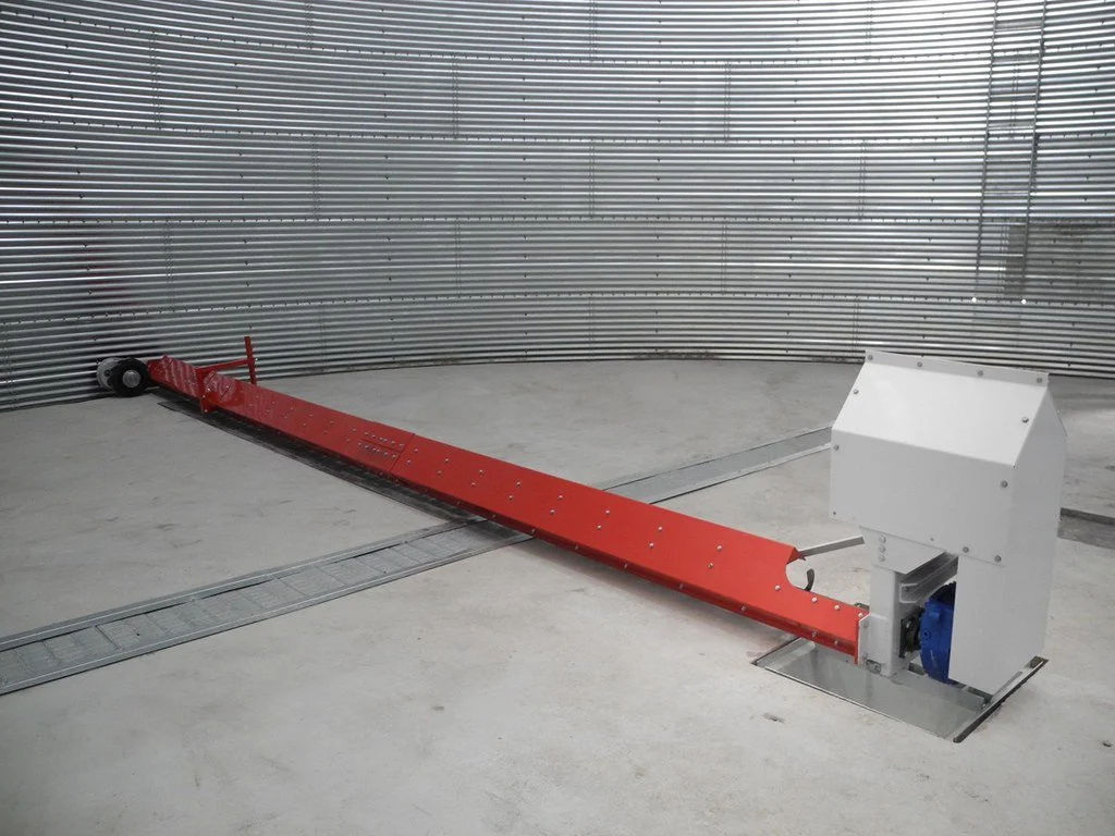 A red rail with a wheel on one end and a white housing with a blue motor attached, installed on a concrete floor inside a dome-shaped room with metallic, layered walls.