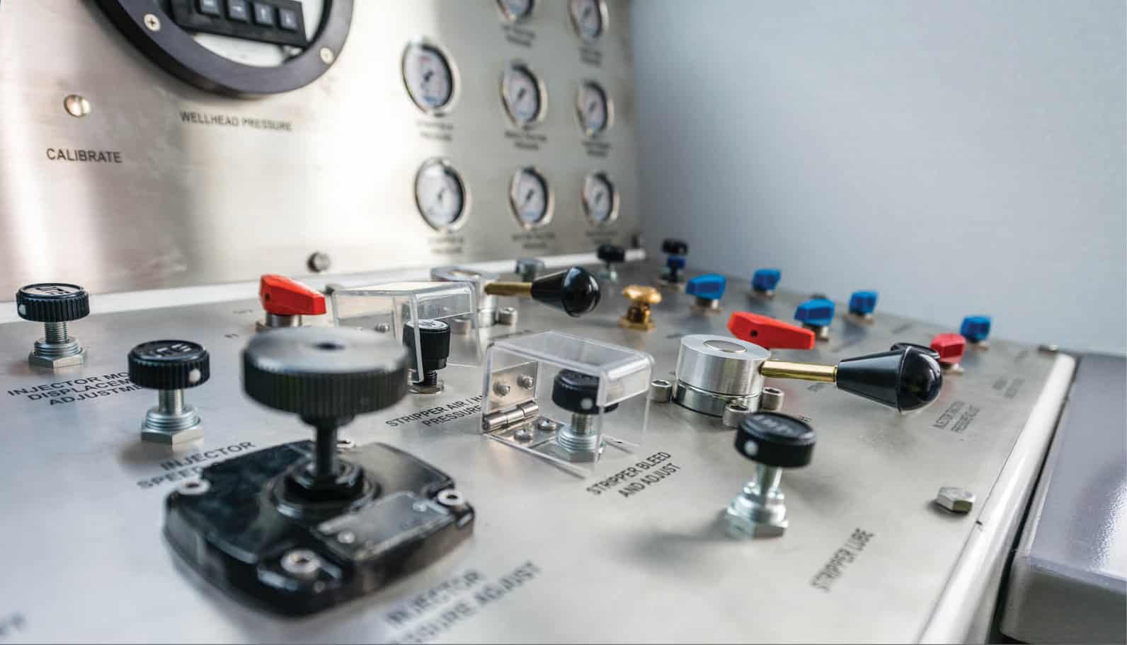 Close-up of a control panel with various dials, levers, and switches, some labeled for adjusting pressure and other settings.
