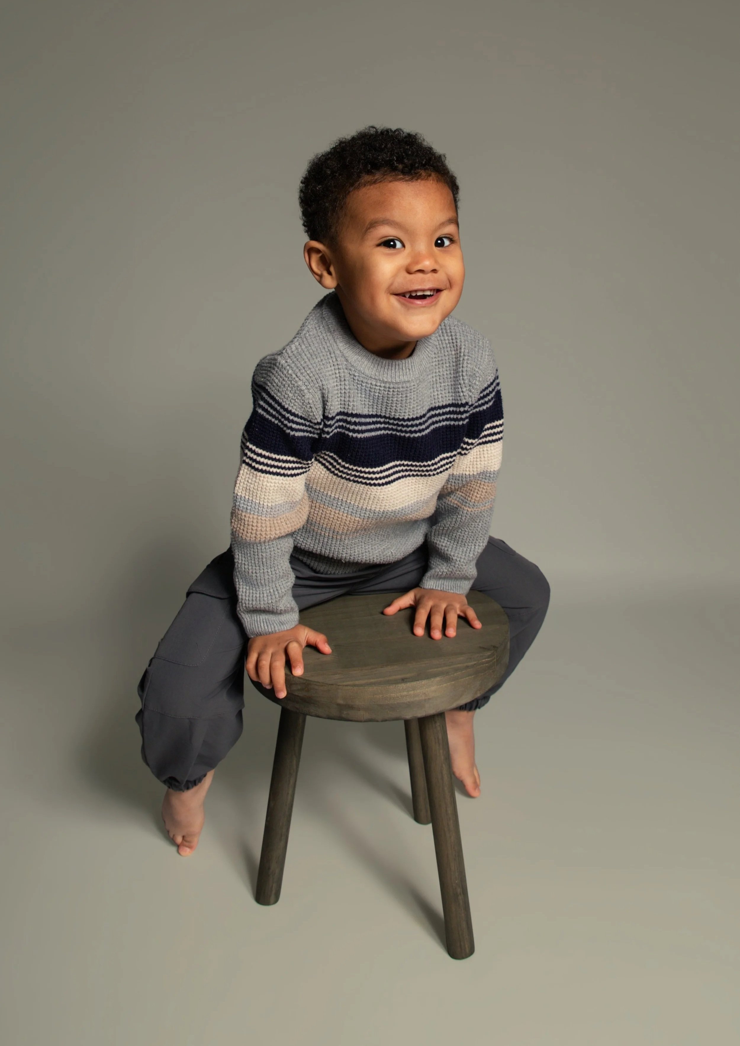 toddler boy sitting on a stool smiling for an at home portrat photograph photoshoot in Bury Manchester. childrens portrait photographer whitefield, Manchester