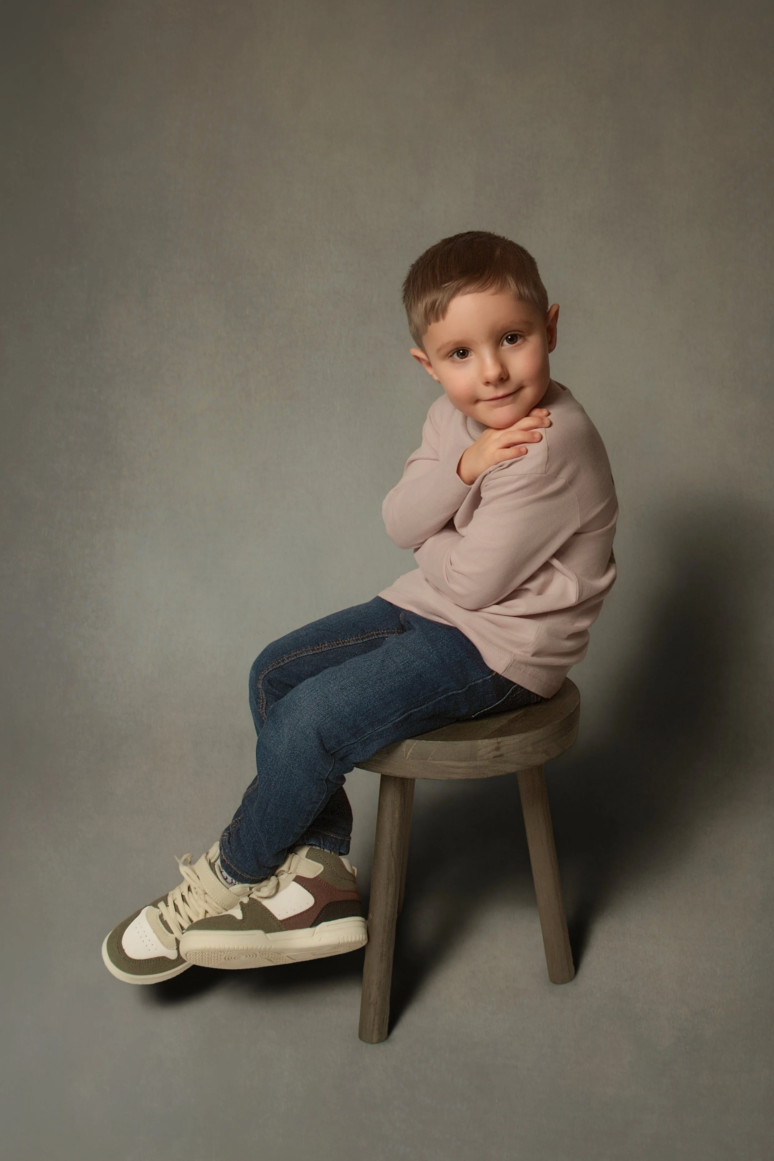 young boy sat on a stool with his feet crosses. an at home childrens and family portrait session in bury manchester