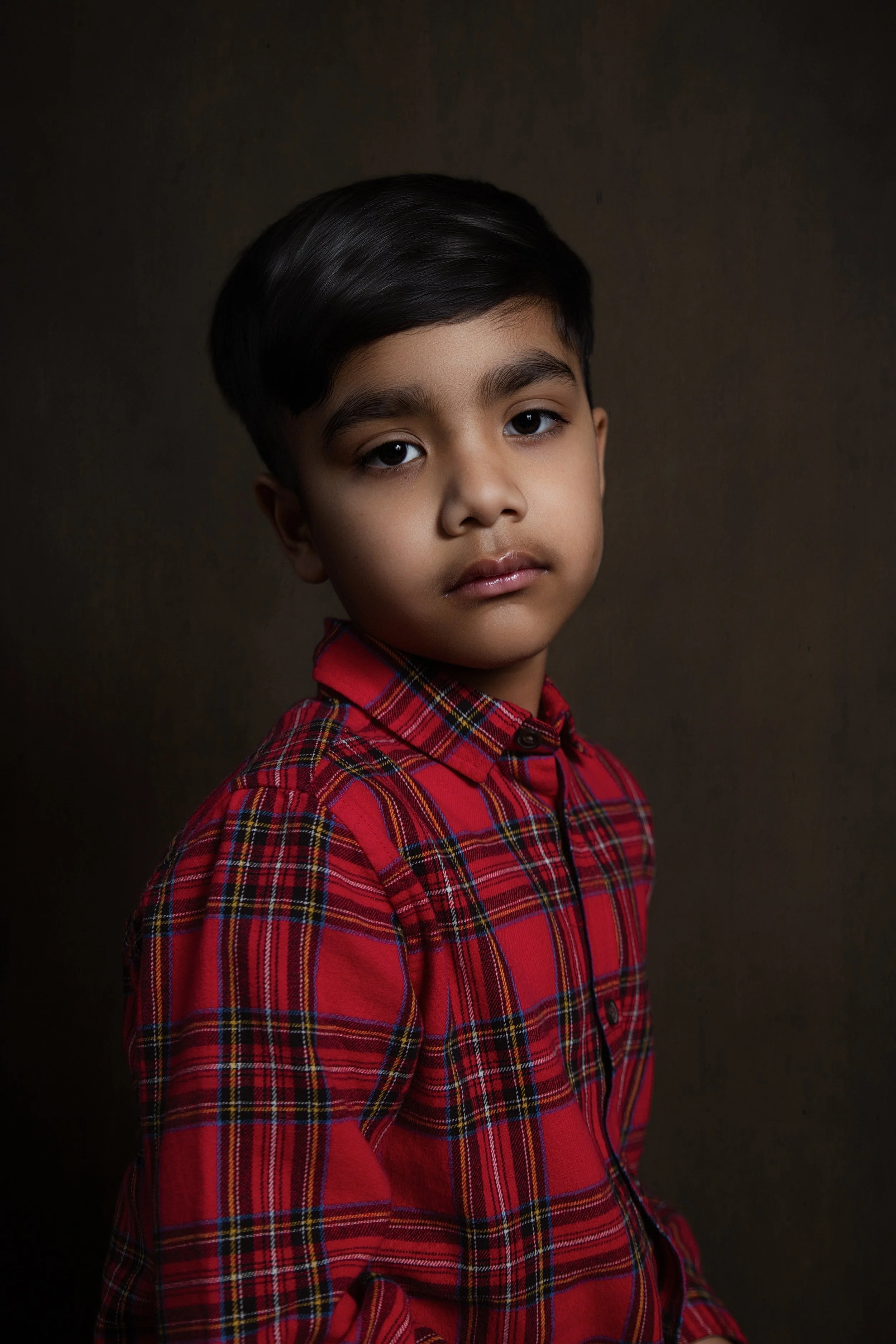 fine art photography of young boy child in red checked shirt with soft subtle lighting in manchester