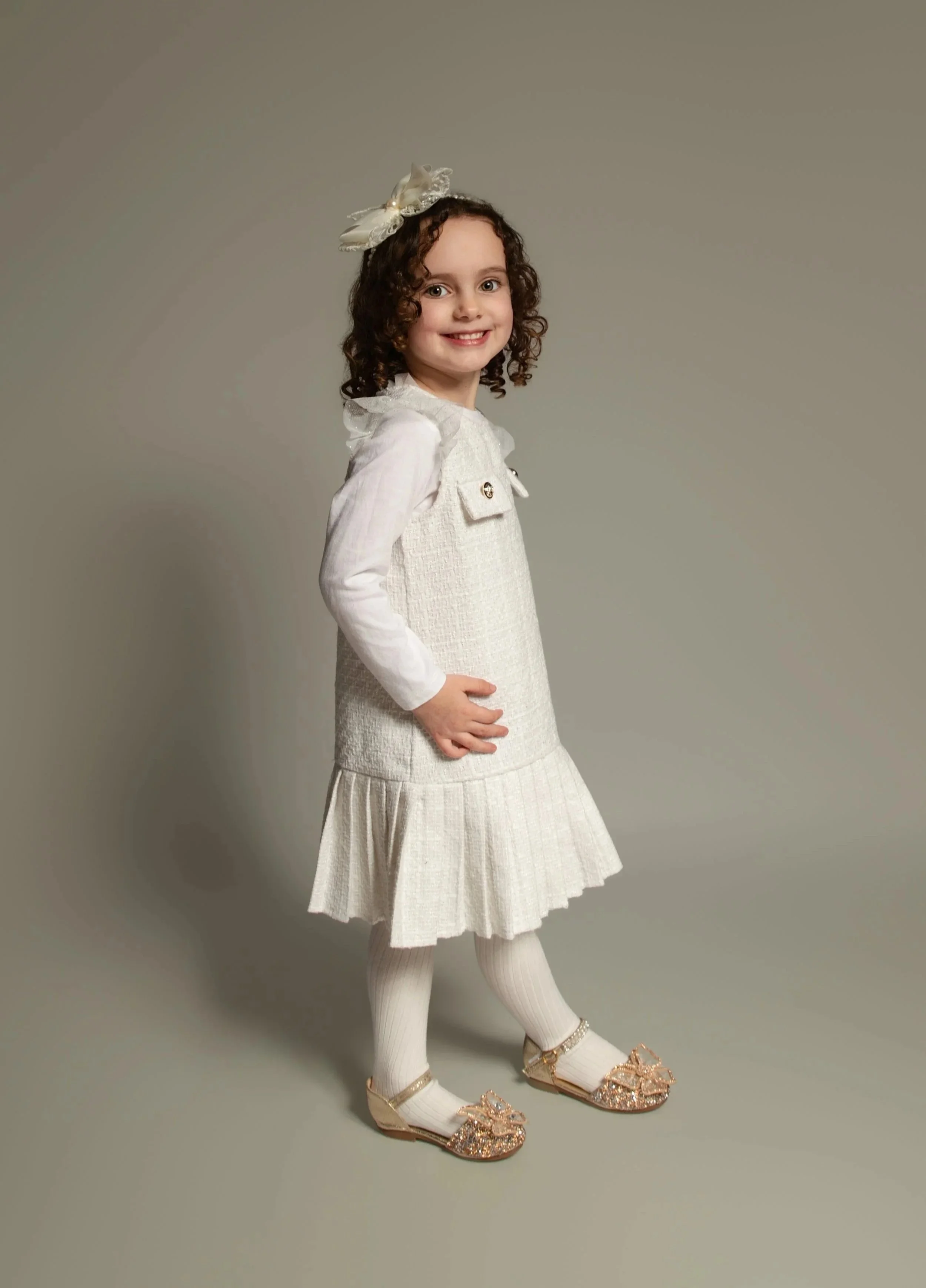little girl in a cream dress with a headband and curly brown hair. childrens portrait photoshoot at home, Whitefield, Manchester