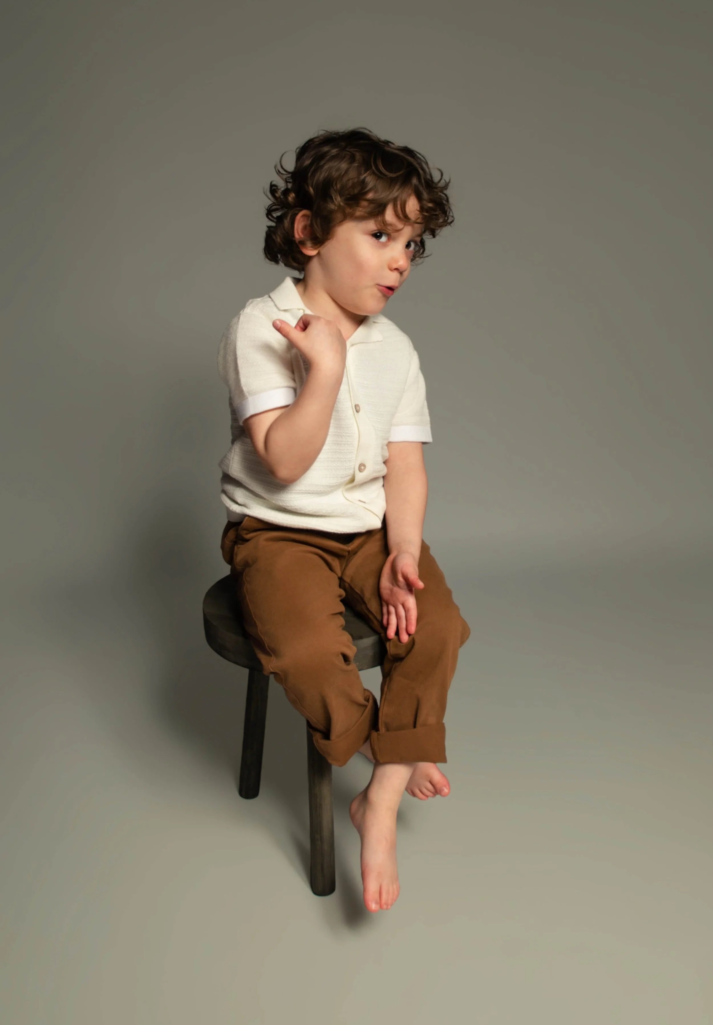 Studio style portrait of four year old boy sitting on stool on neutral background, hosted portrait session in Bury, Manchester