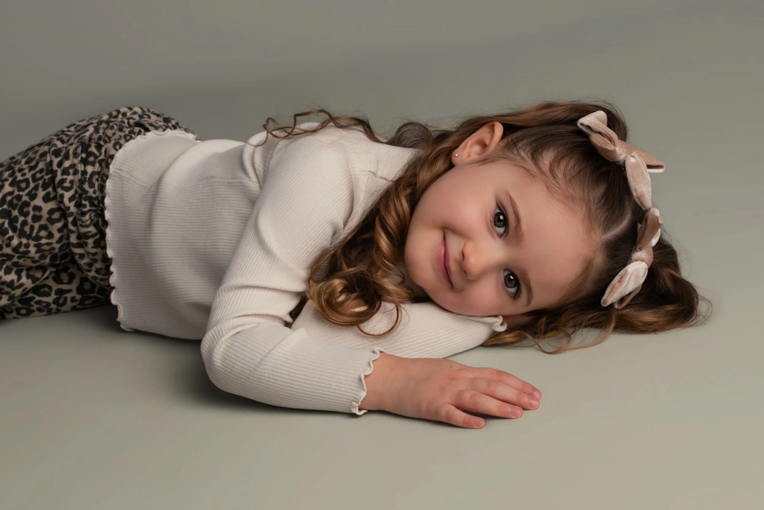 Natural at-home close-up portrait of young girl lying on the floor, captured in a relaxed and authentic style.