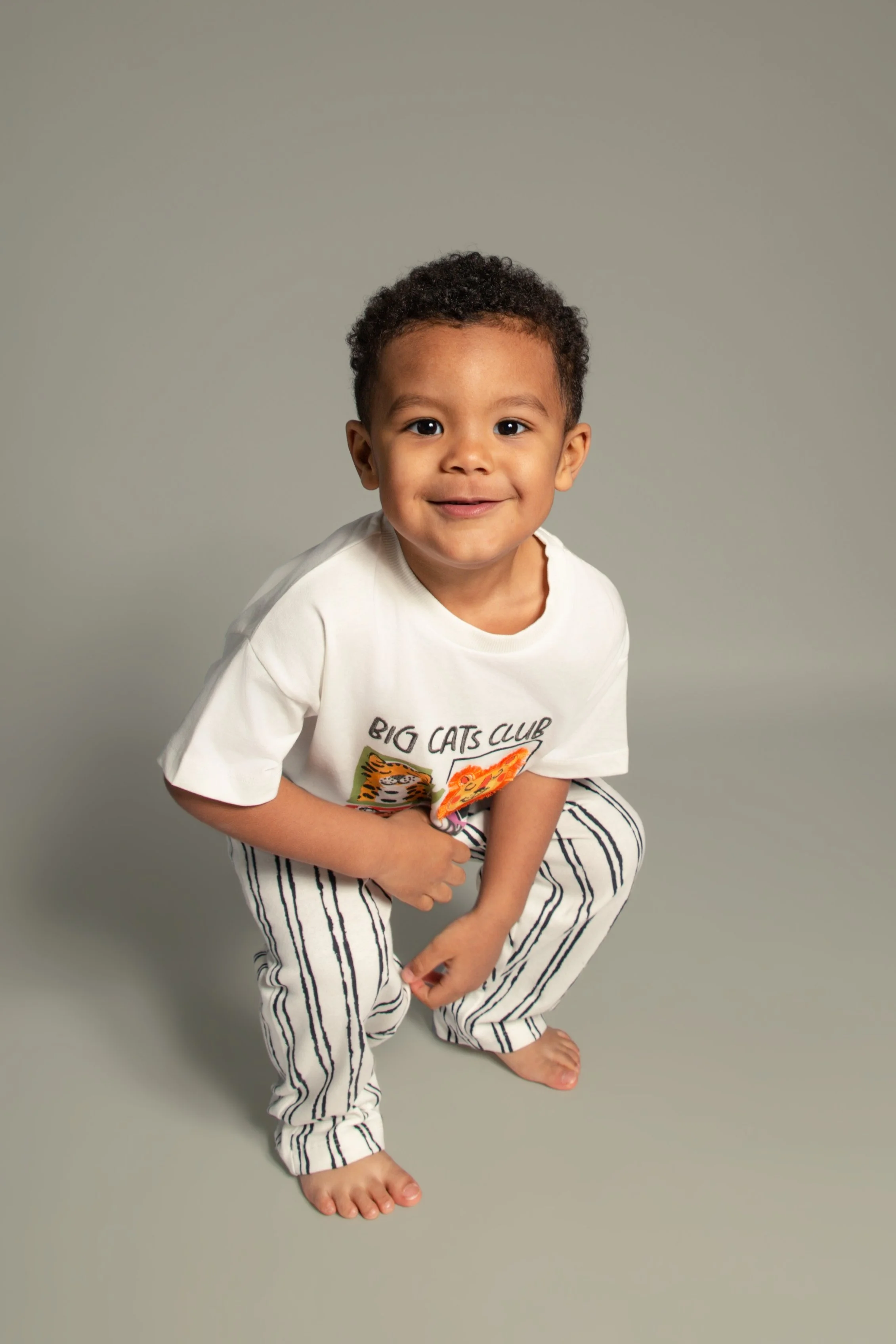 Young child crouching down and smiling for his photoshoot with Bury Manchester Children,s family portrait photographer