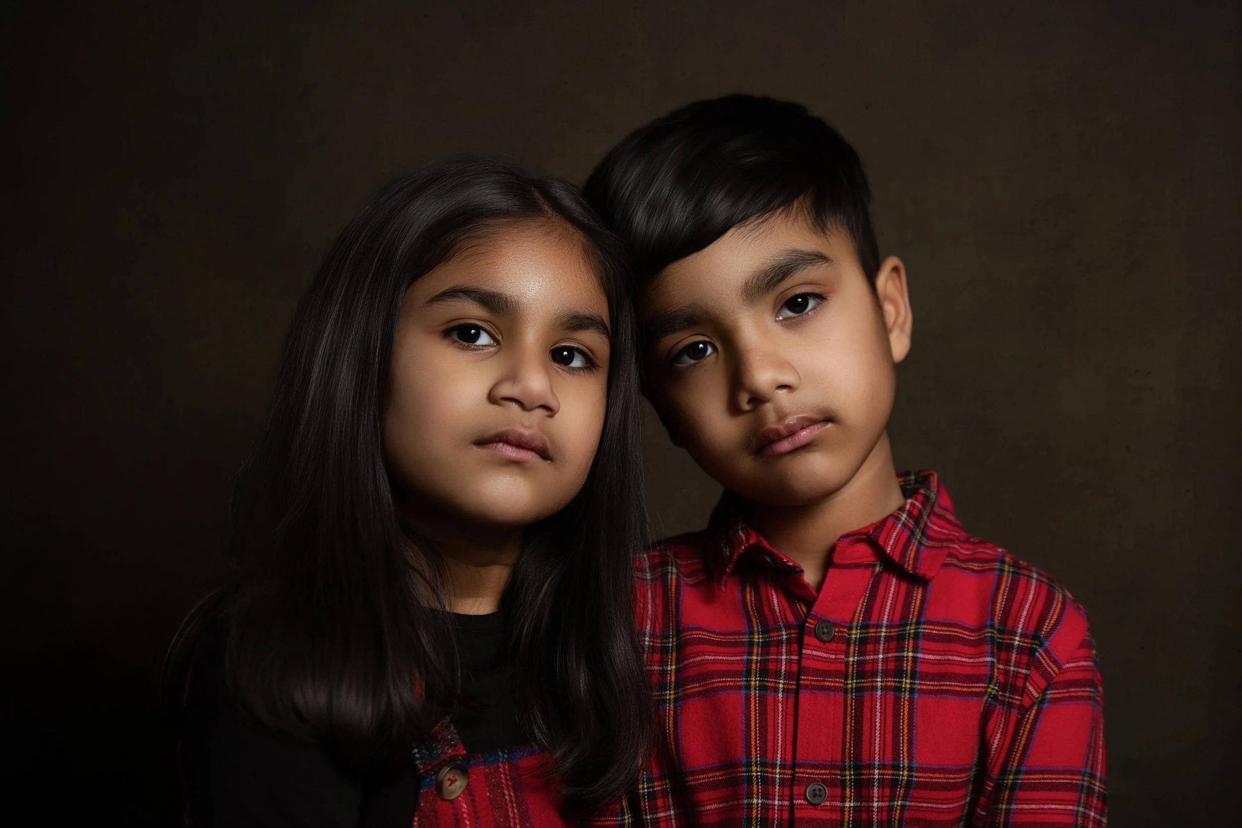 beautiful fine art portrait of sibling brother and sister with warm tones showing their family bond on a dark background in Whitefield