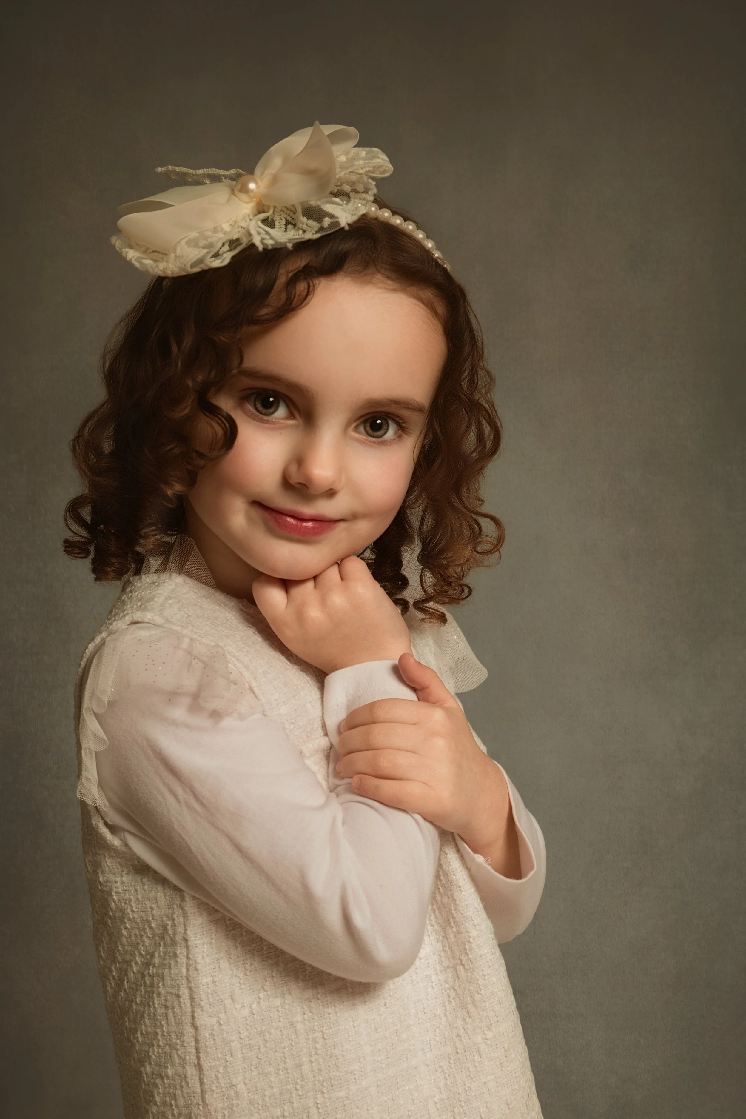 classic little girl fine art portrait by manchester Bury  family portrait photographer. Young girl with curly brown hair looking straight at the camera with bright eyes. Vintage style