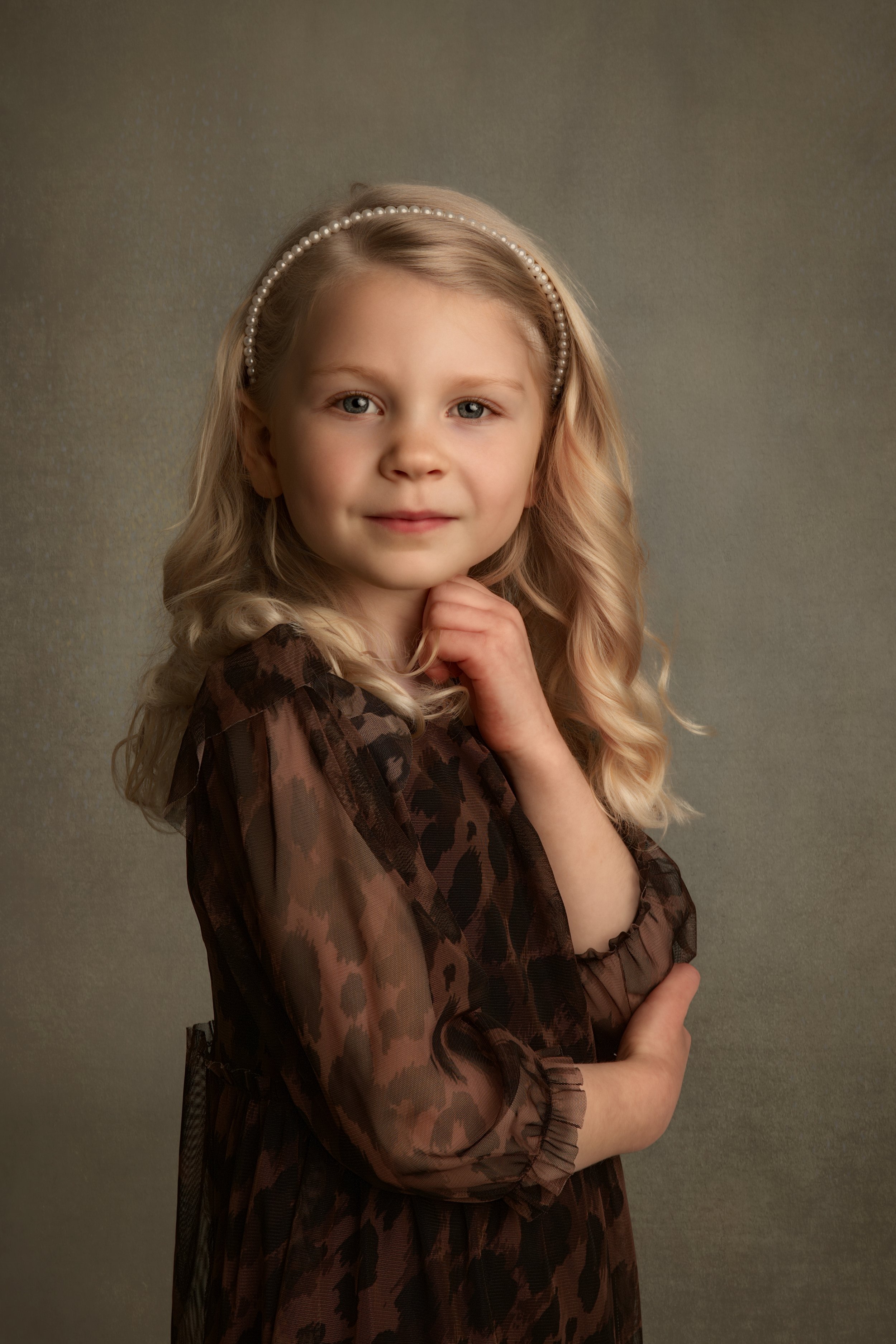 Fine art children’s close-up portrait of young girl with a soft, classic style and neutral backdrop, photographed in a timeless fine art style.