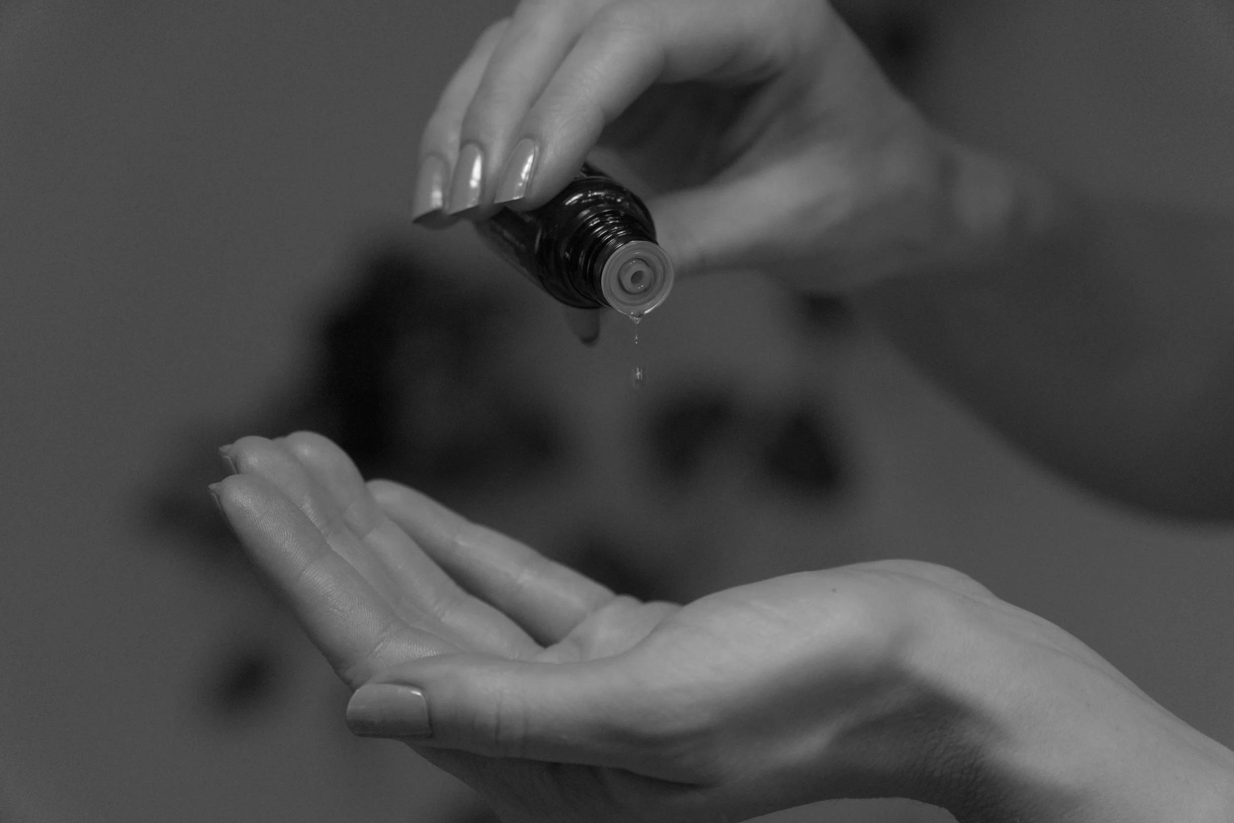 Jemand träufelt eine medizinische Substanz aus einer Braunflasche in die Handfläche.