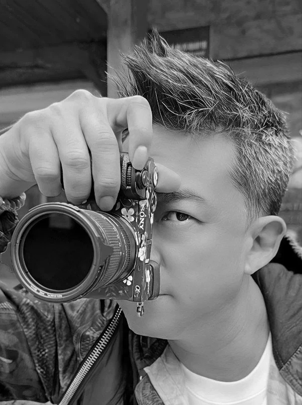 Young boy with spiky hair looking through a camera, taking a photo.