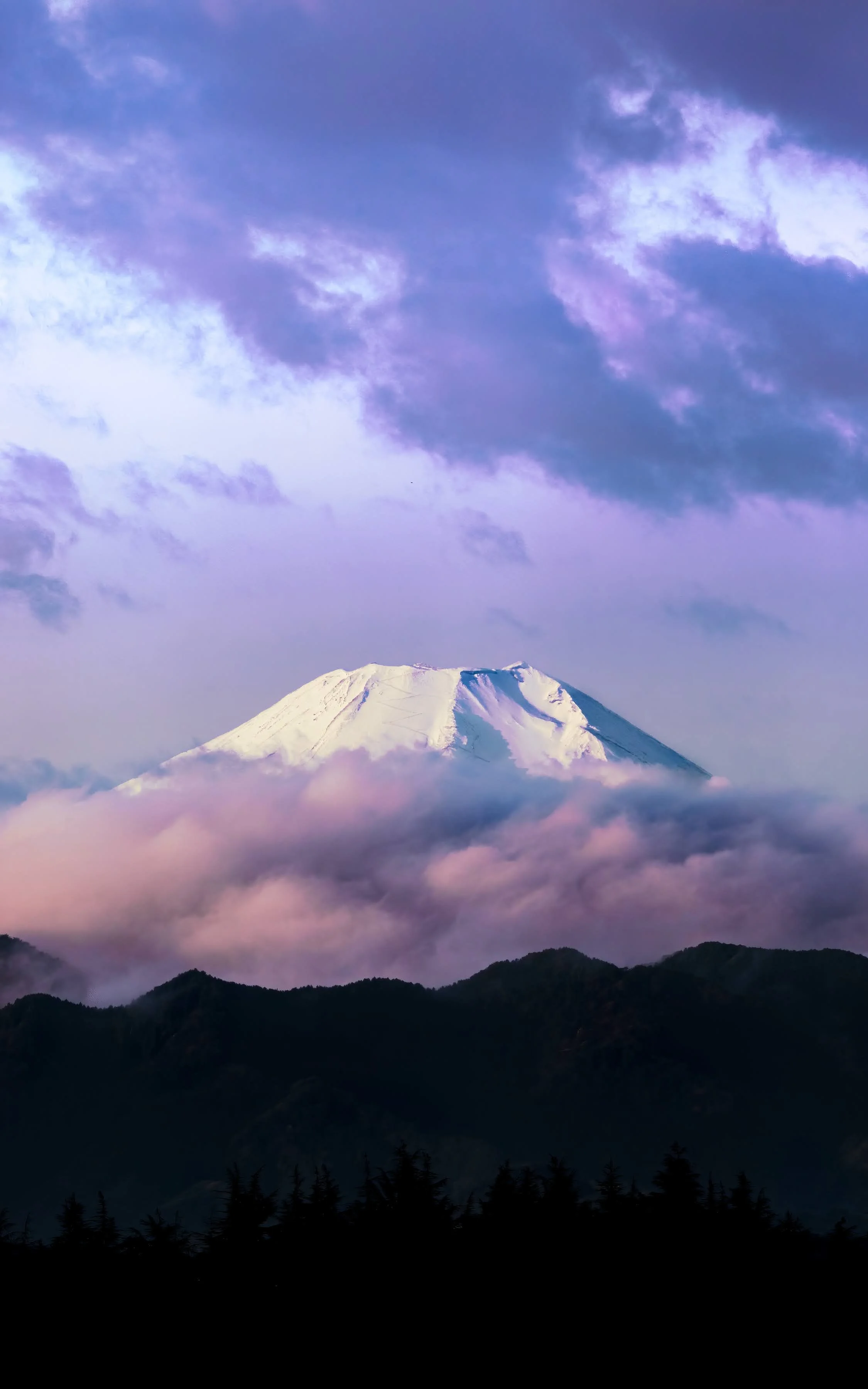 Snow-capped mountain with clouds and purple sky.
