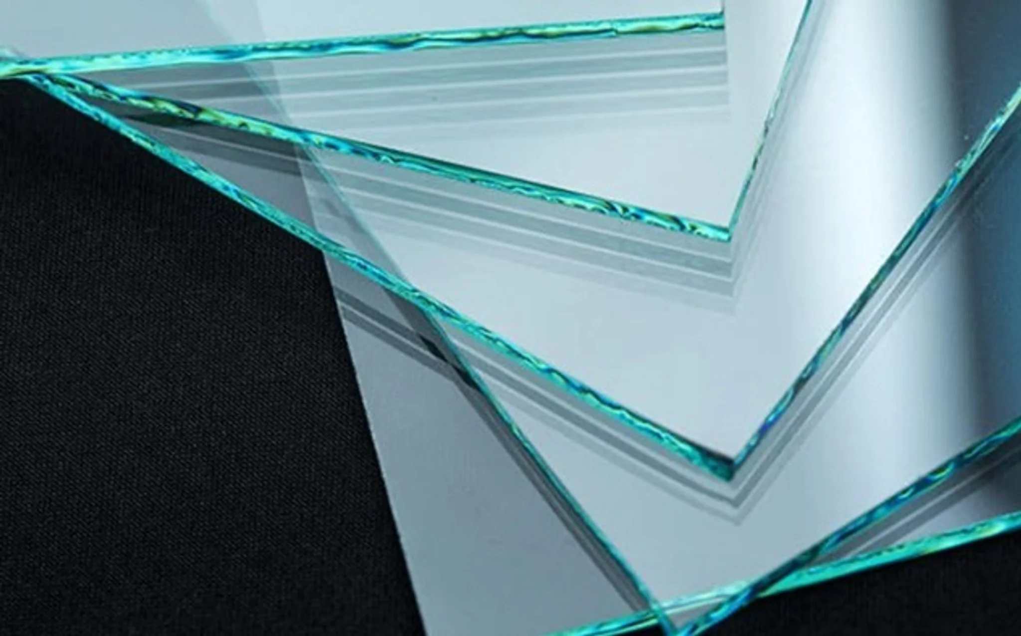 Une collection de plaques en verre transparent avec des bords lumineux bleus et verts, placées sur une surface noire.