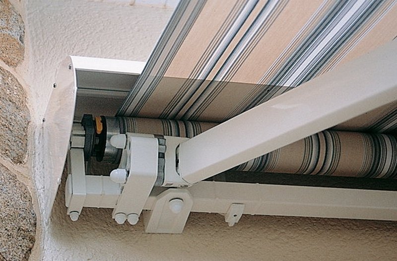 Vue au ras du sol d'une porte moustiquaire en métal avec un sol en marbre, à l'extérieur on voit des arbres verts et un ciel bleu.