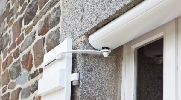 Caméra de sécurité et détecteur de mouvement installés à côté d'une fenêtre en pierre