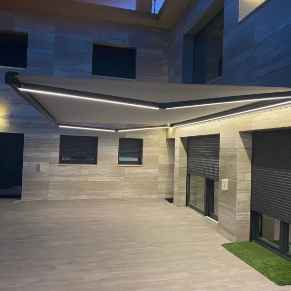 Terrasse extérieure moderne avec clôture en bois, fenêtres à volets roulants, et un store banne avec éclairage intégré dans le Rhône