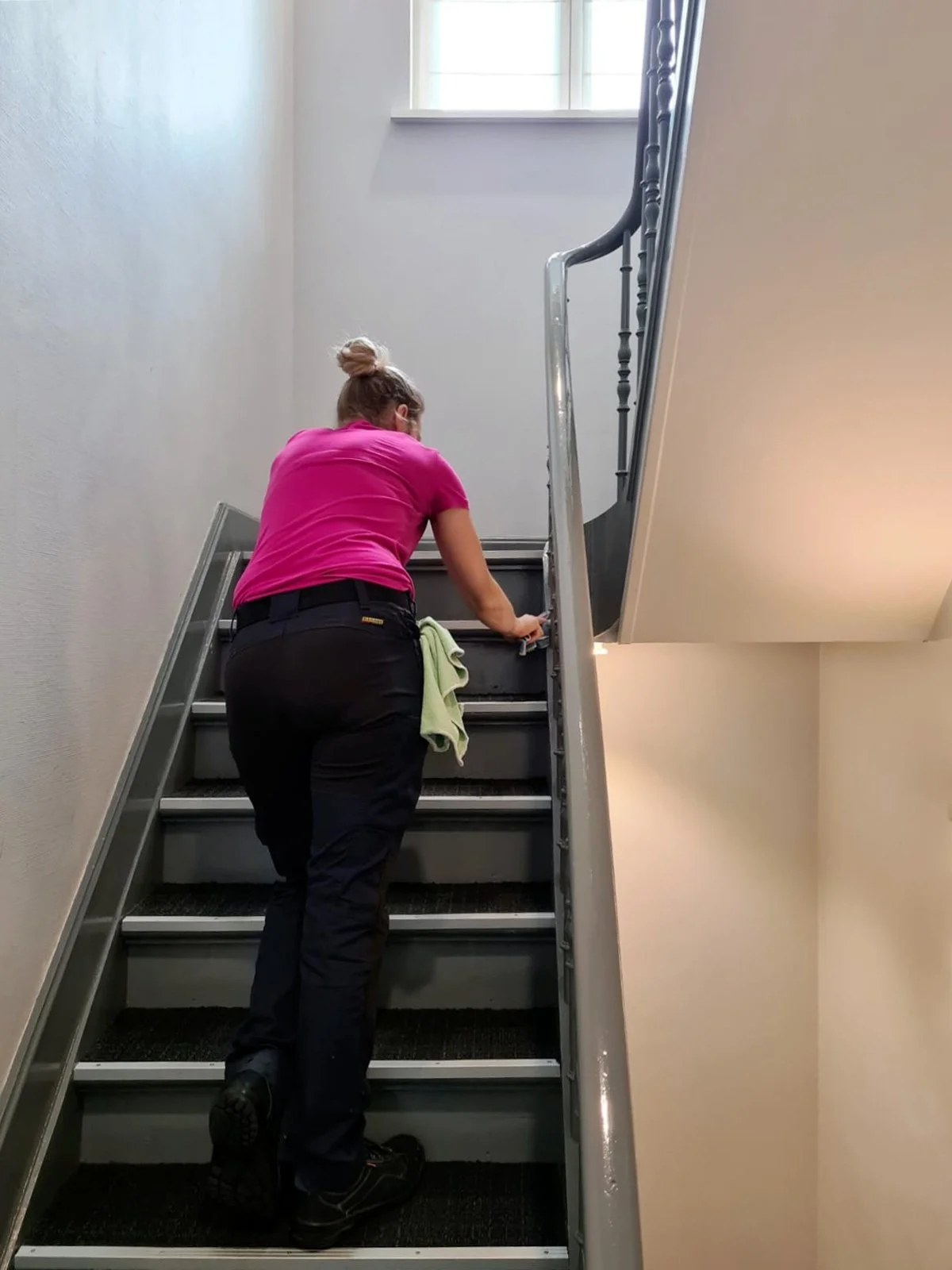 Vrouw poetst de trap in een gebouw.