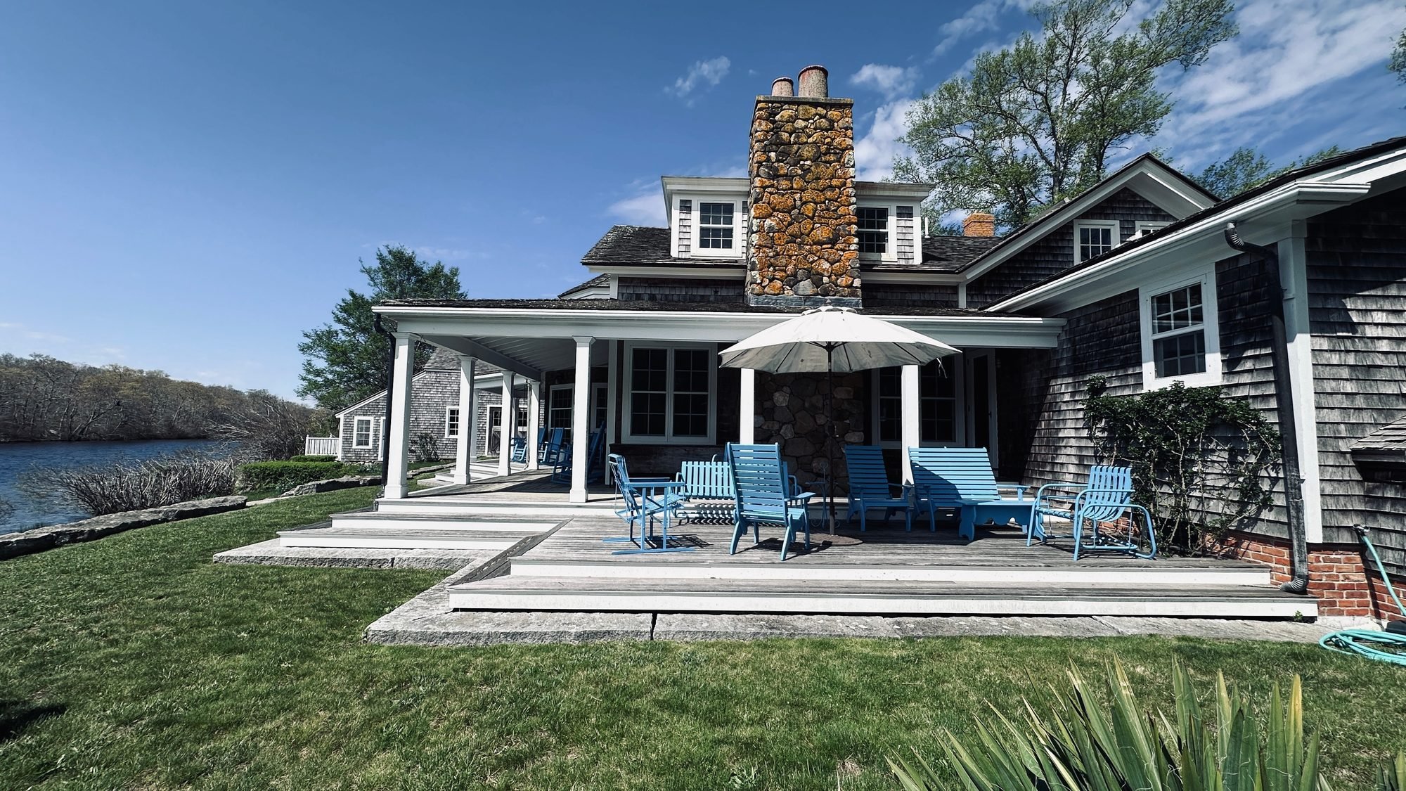 Shingled West Tisbury farmhouse with a wraparound porch and stone patio overlooking Mill Pond
