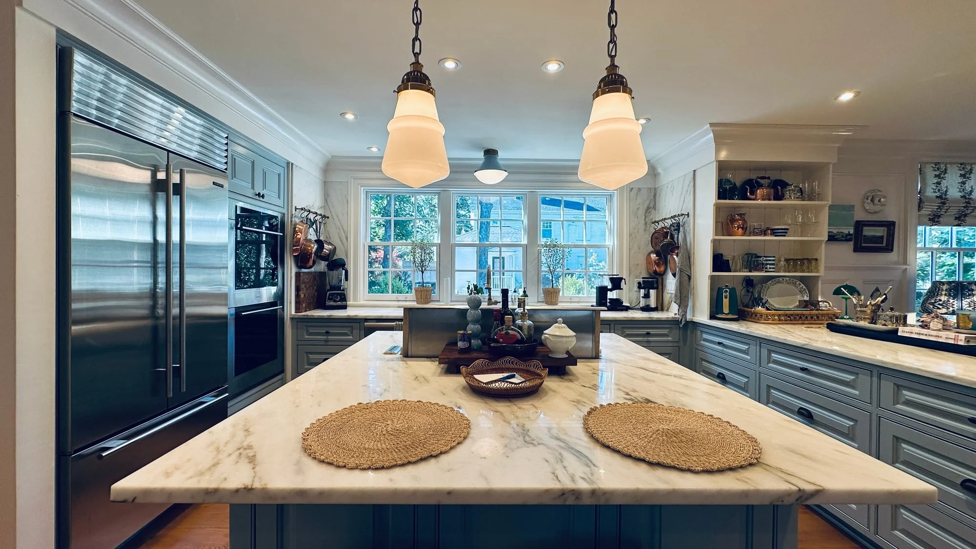 Bright kitchen with a marble island under schoolhouse pendants in Vineyard Haven