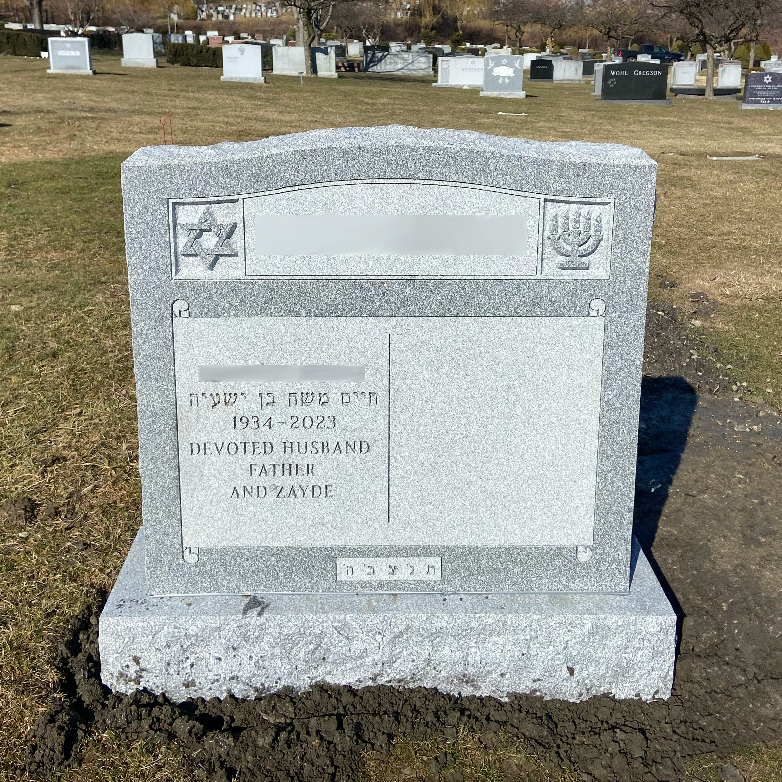 Upright double granite monument with personalized engraving, decorative carving, and religious detail.