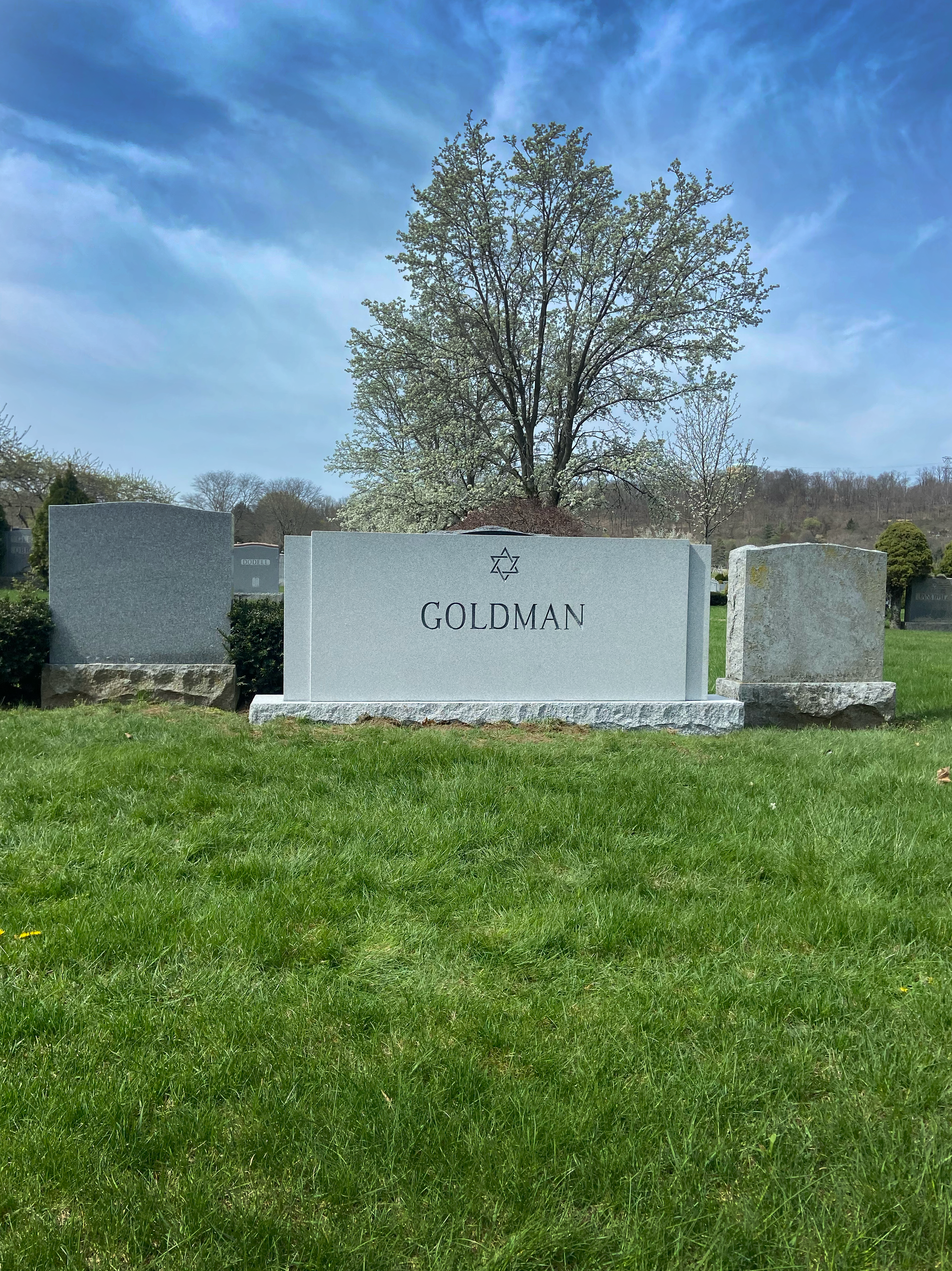 Custom family granite monument with engraved text in a beautiful cemetery.