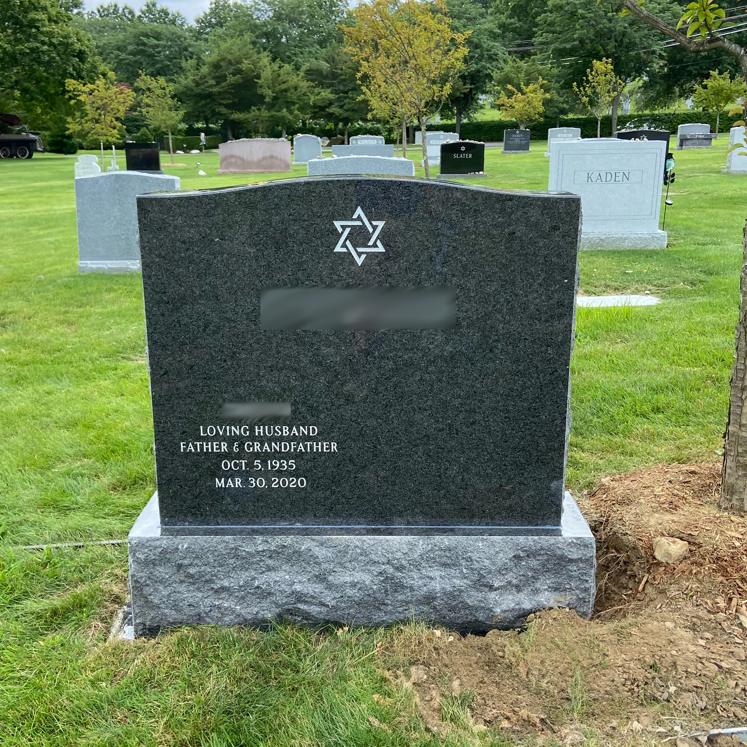 Upright double granite monument with personalized engraving, decorative carving, and religious detail.