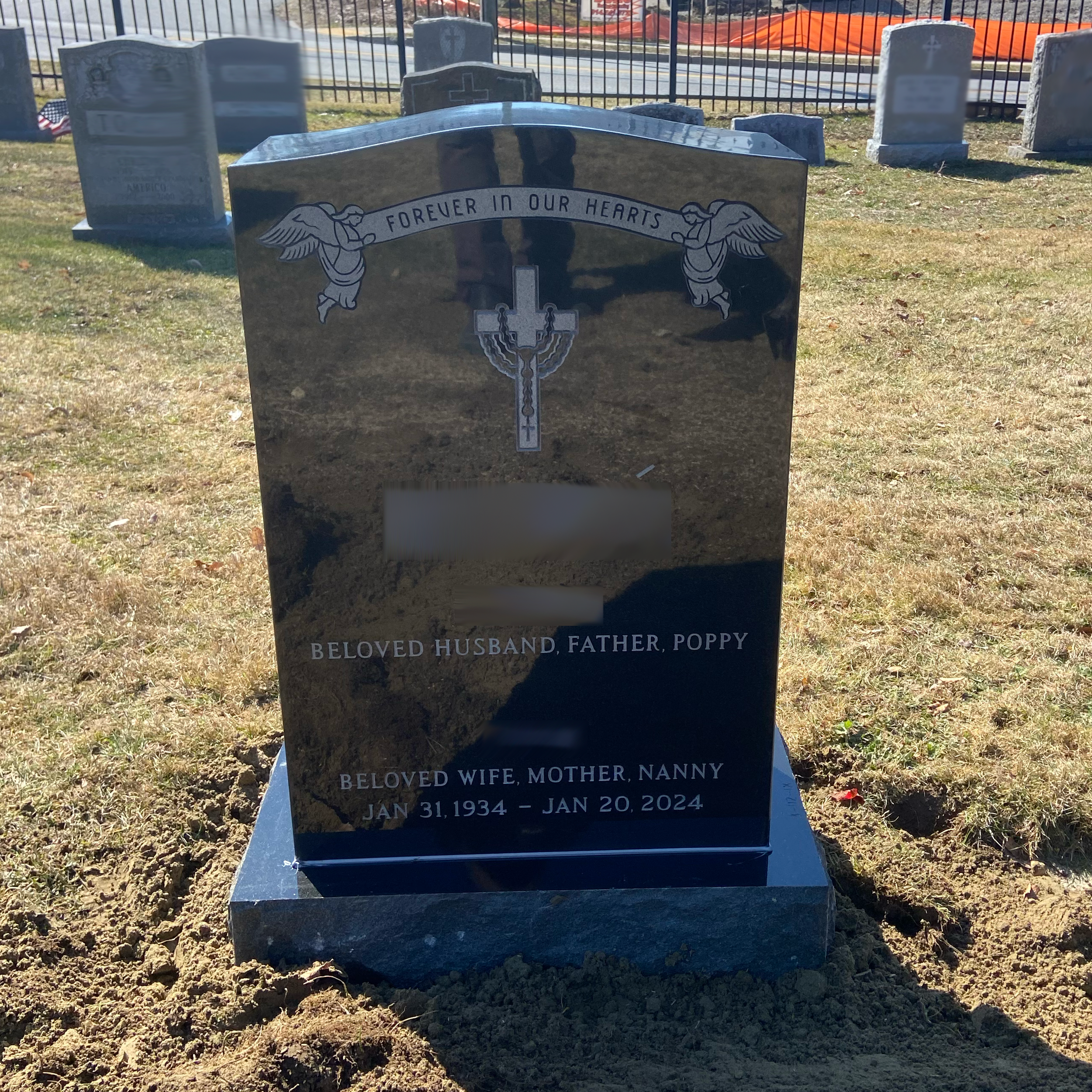 Upright granite monument with personalized engraving, decorative carving, and religious detail.
