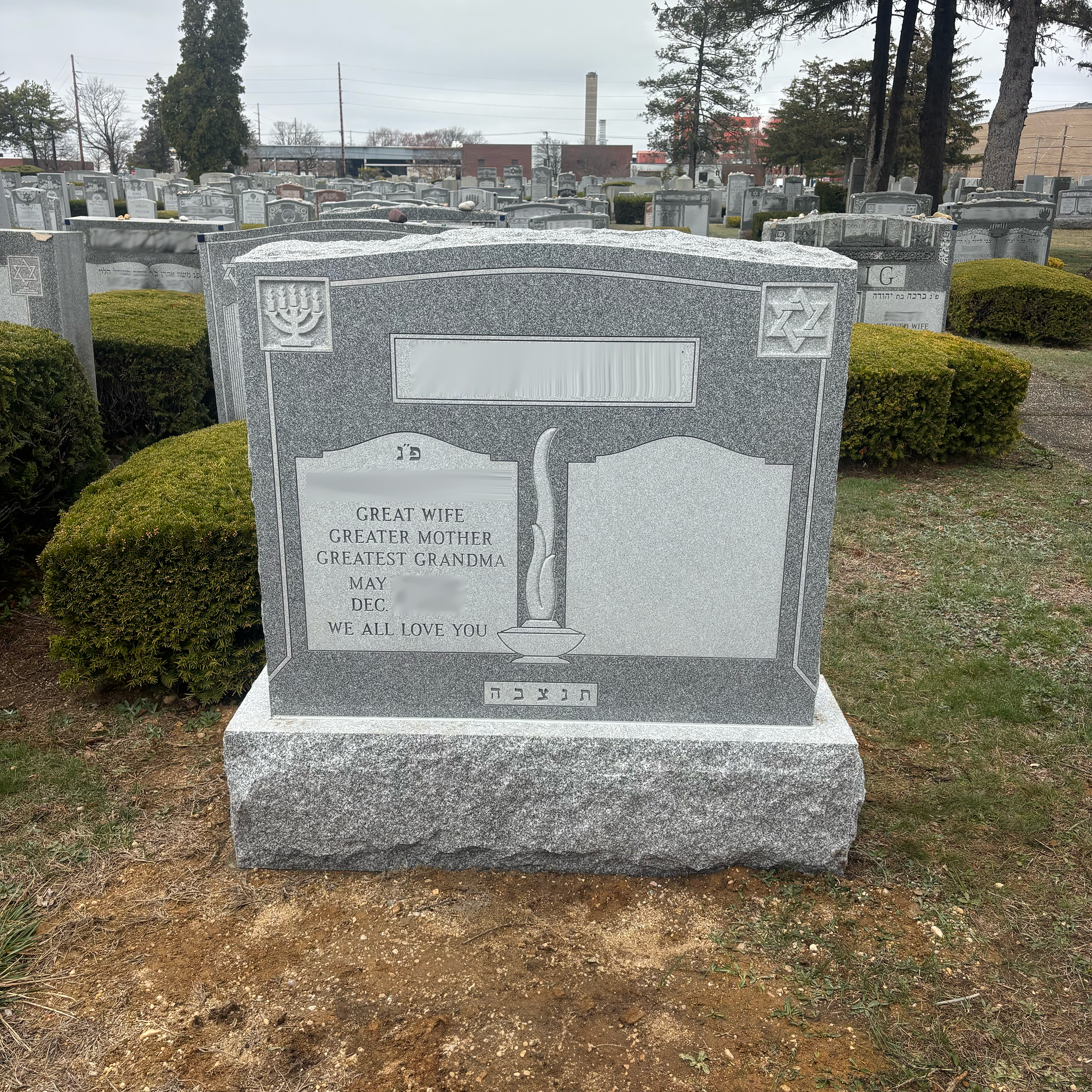 Upright double granite monument with personalized engraving, decorative carving, and religious detail.