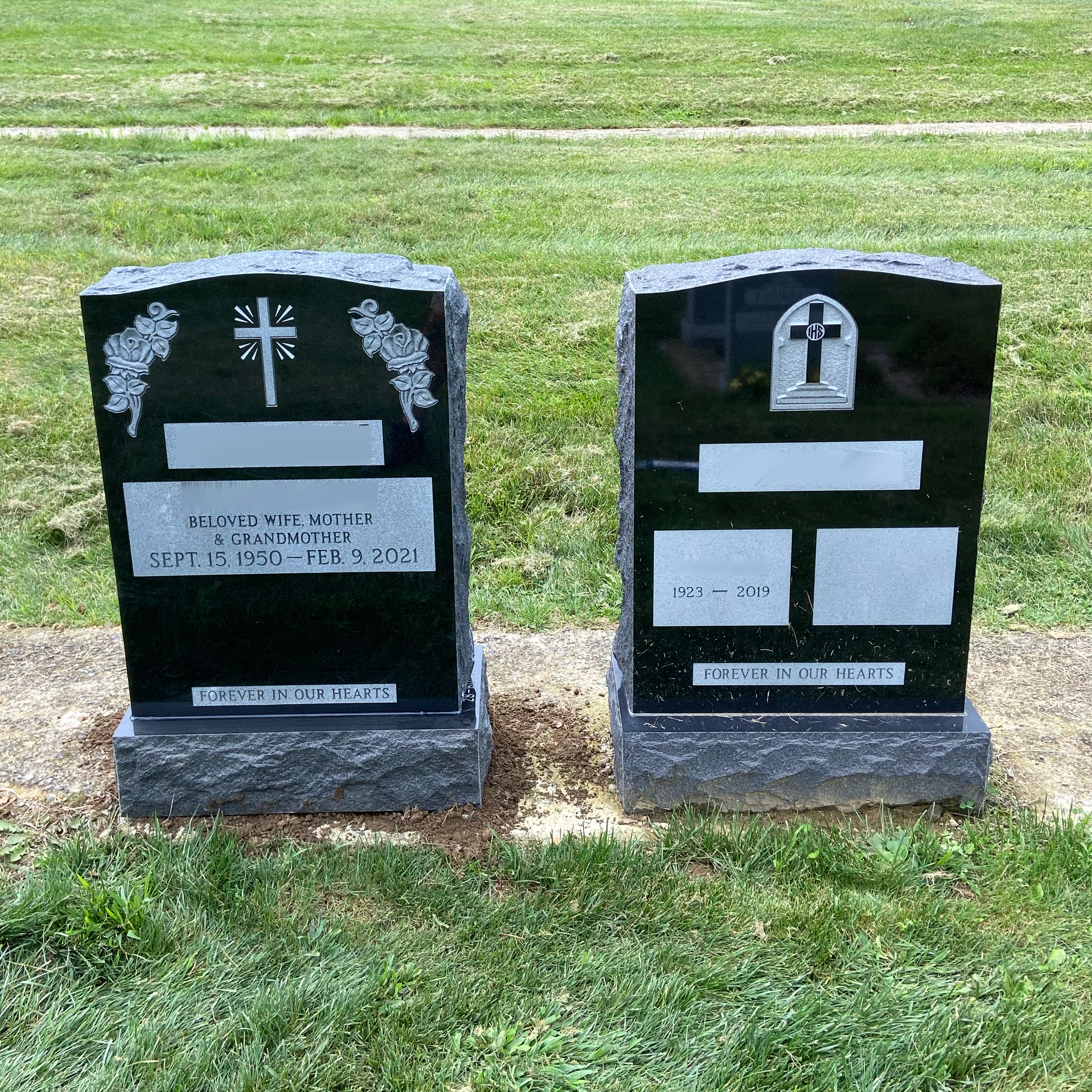 Two separate upright granite monuments with personalized engraving, decorative carving, and religious detail.