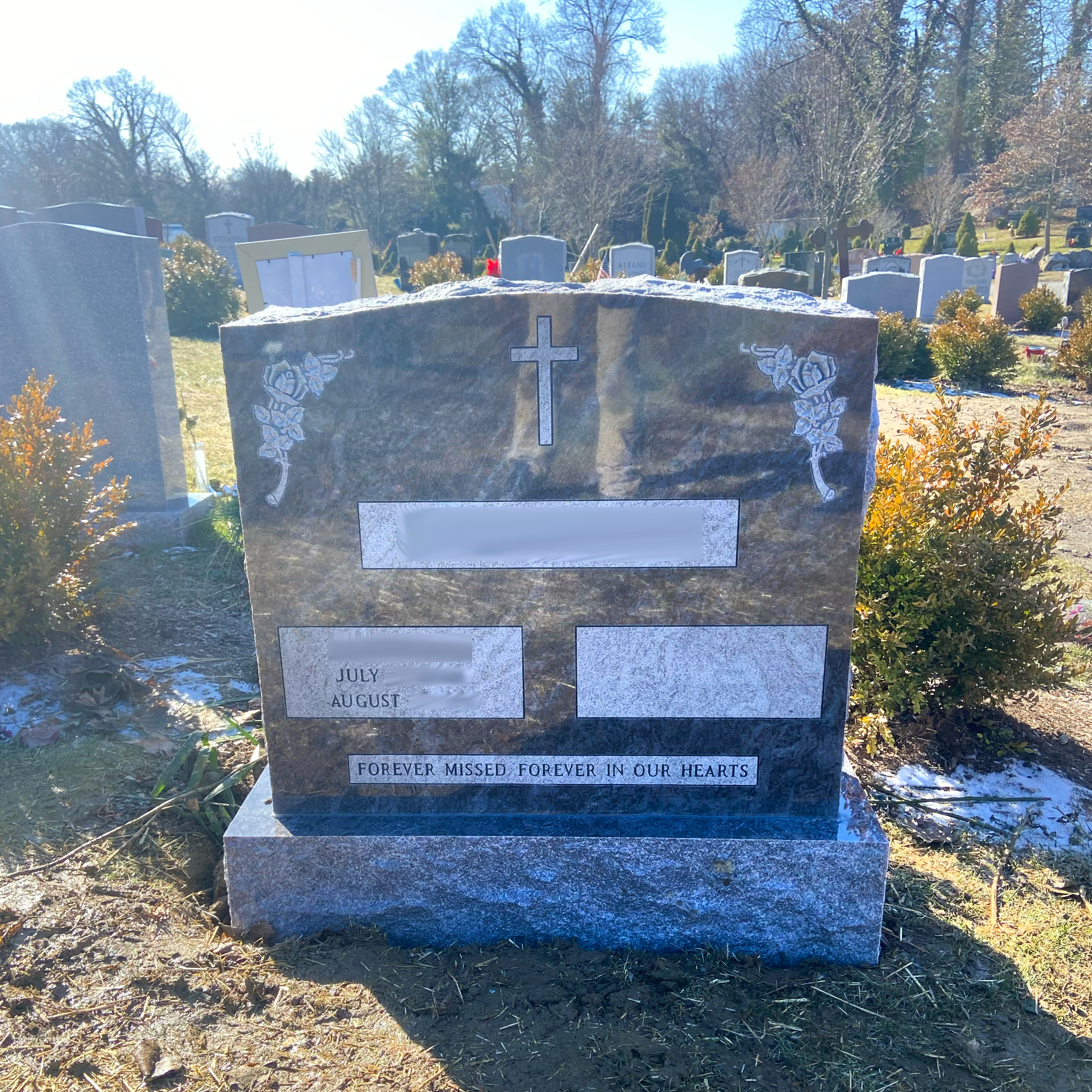 Upright double granite monument with personalized engraving, decorative carving, and religious detail.
