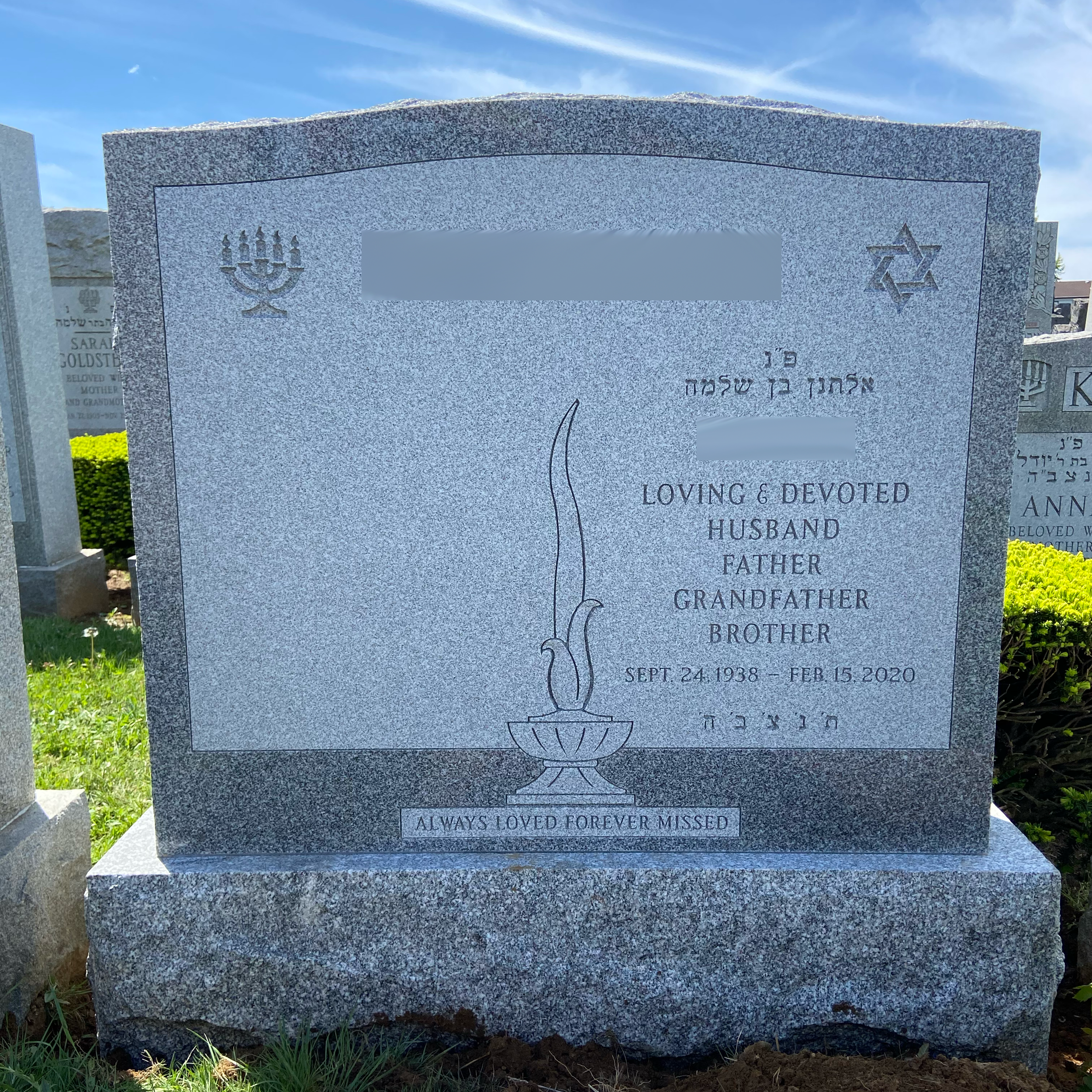 Upright double granite monument with personalized engraving, decorative carving, and religious detail.