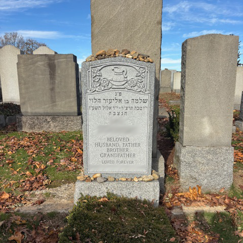 Upright granite monument with personalized engraving, decorative carving, and religious detail.
