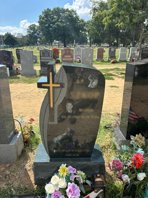 Upright granite monument with personalized engraving, decorative carving, and religious detail.