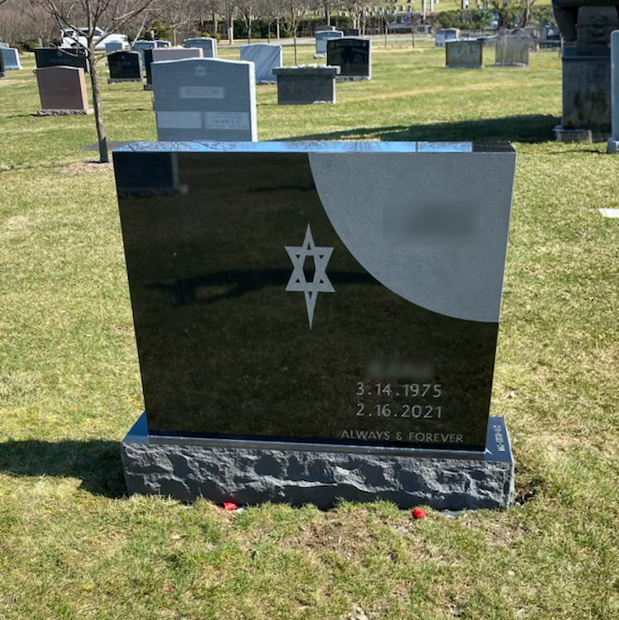 Upright granite monument with personalized engraving, decorative carving, and religious detail.