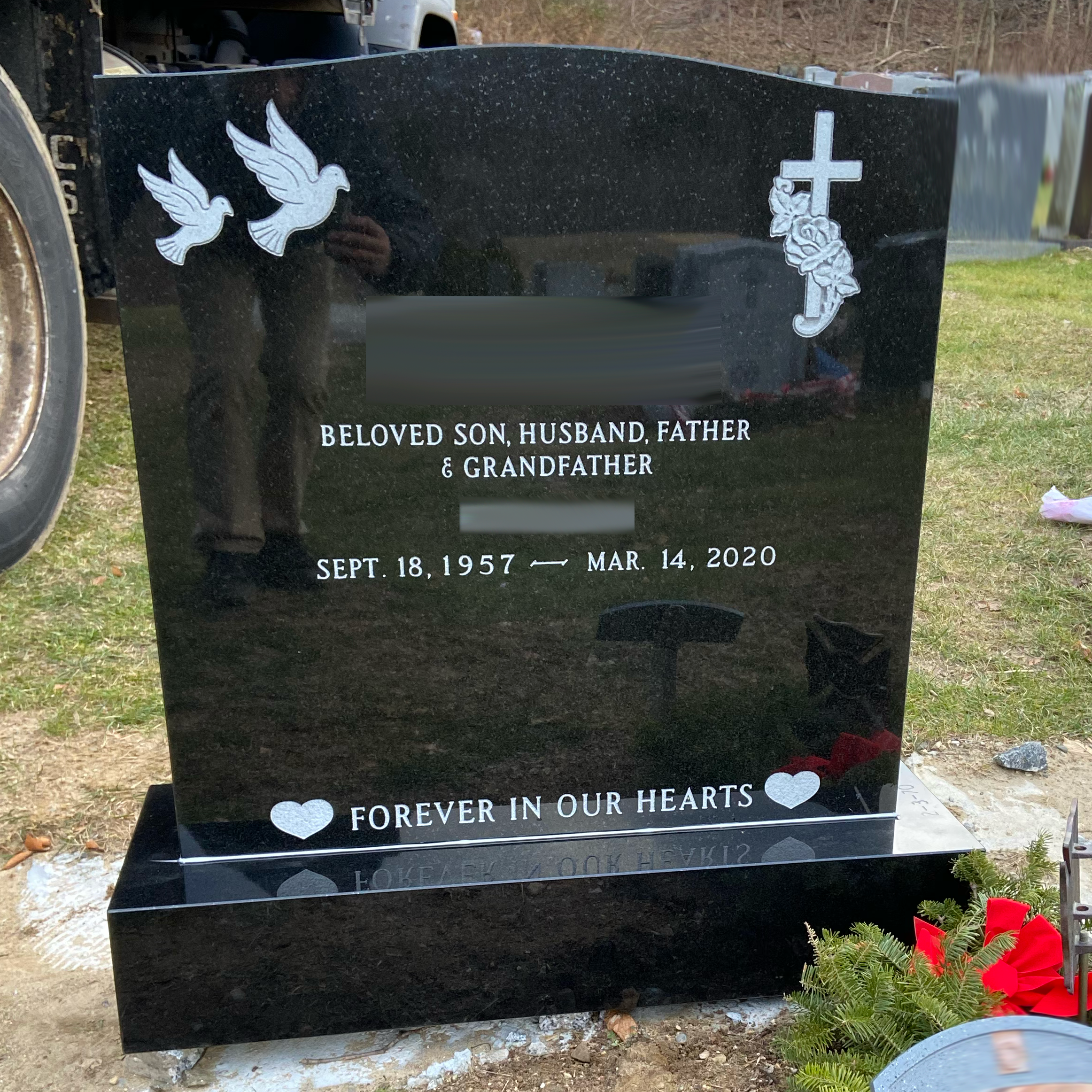 Upright double granite monument with personalized engraving, decorative carving, and religious detail.