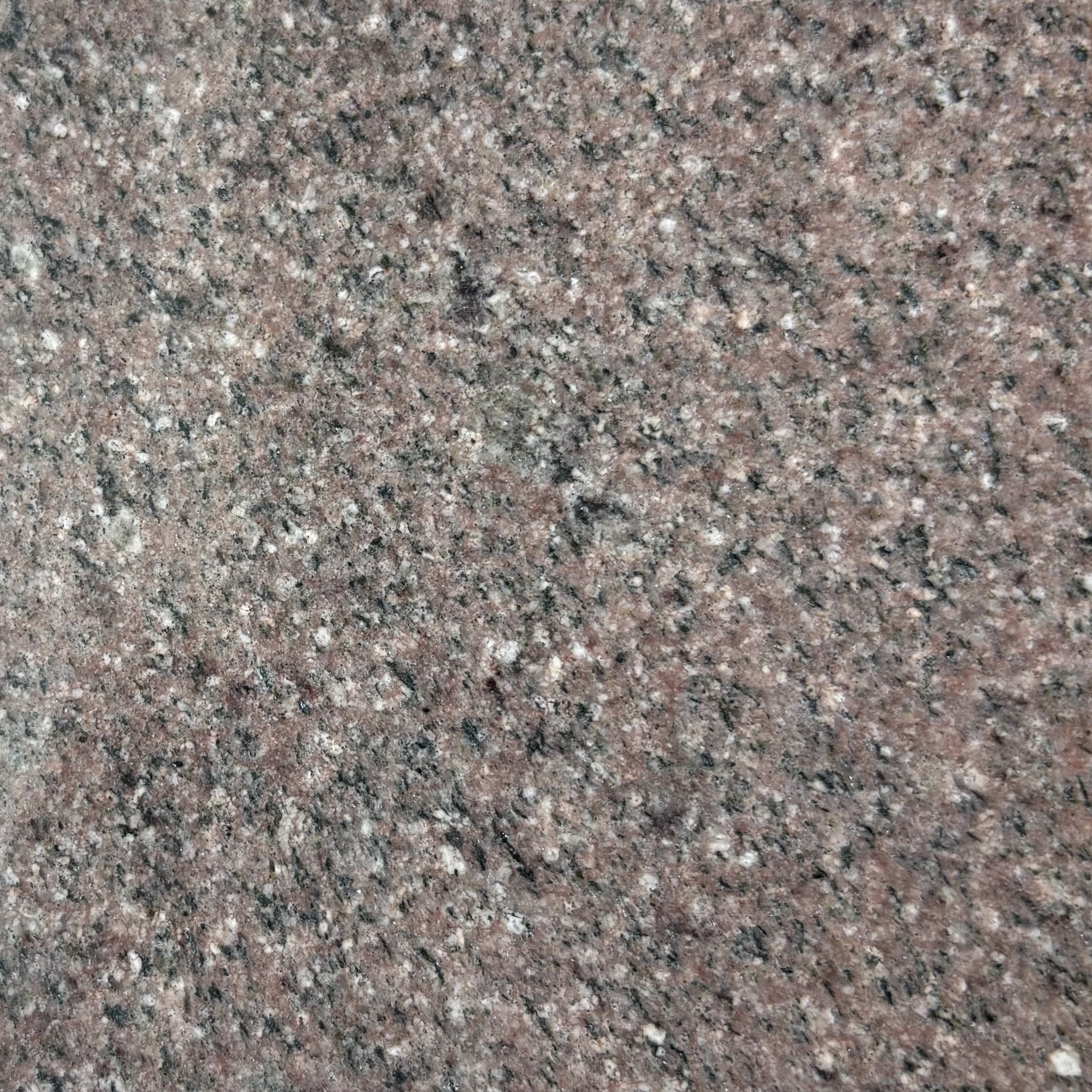 Close-up of Pink Rose, speckled granite countertop with a predominantly brown, light pink, and black pattern.