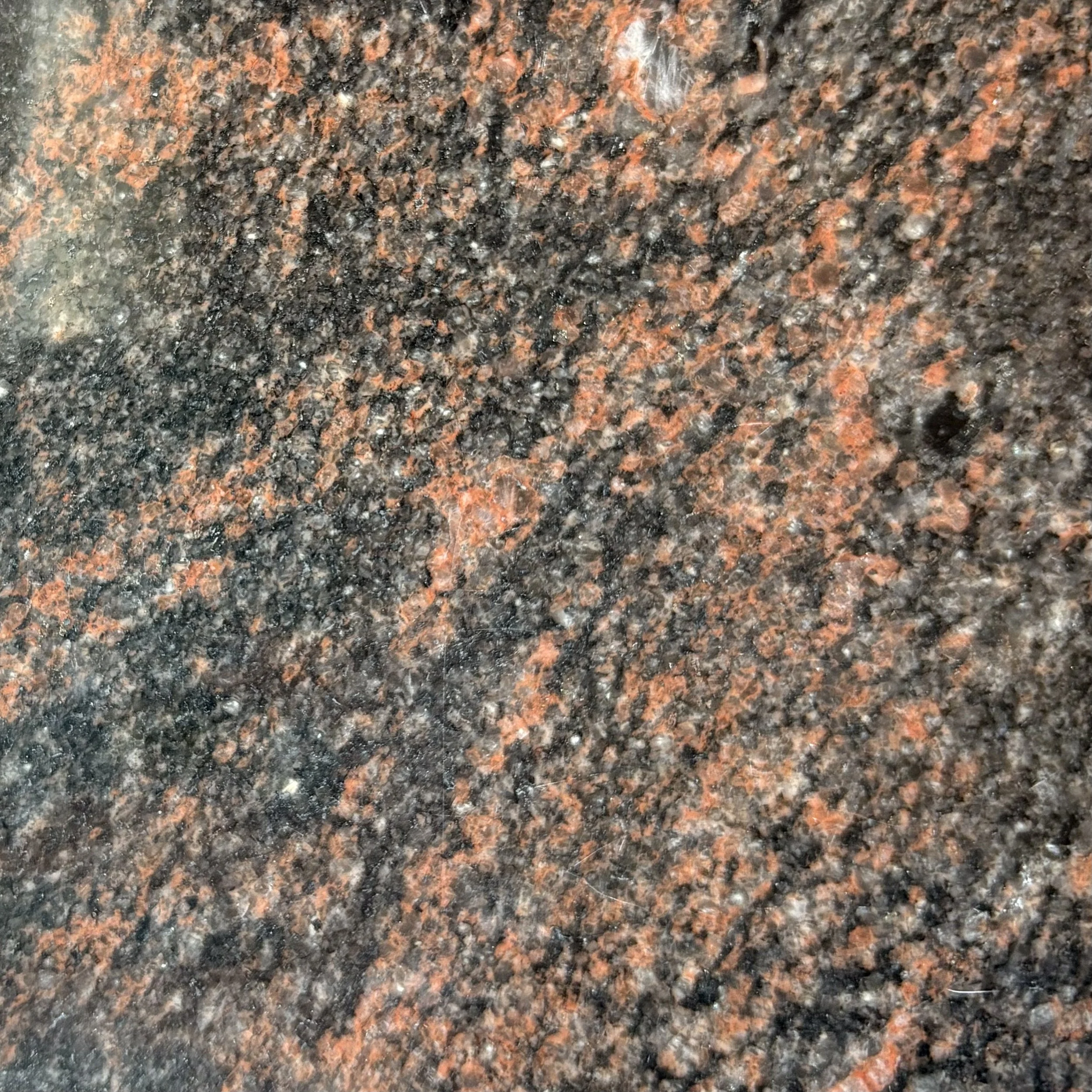 Close-up of a polished Aurora granite with black, red, and gray speckles.